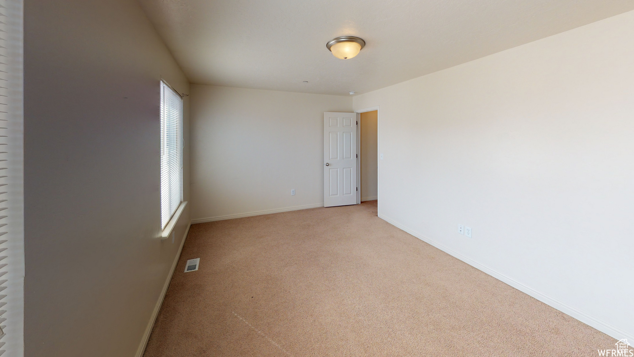 Empty room with light carpet, visible vents, and baseboards