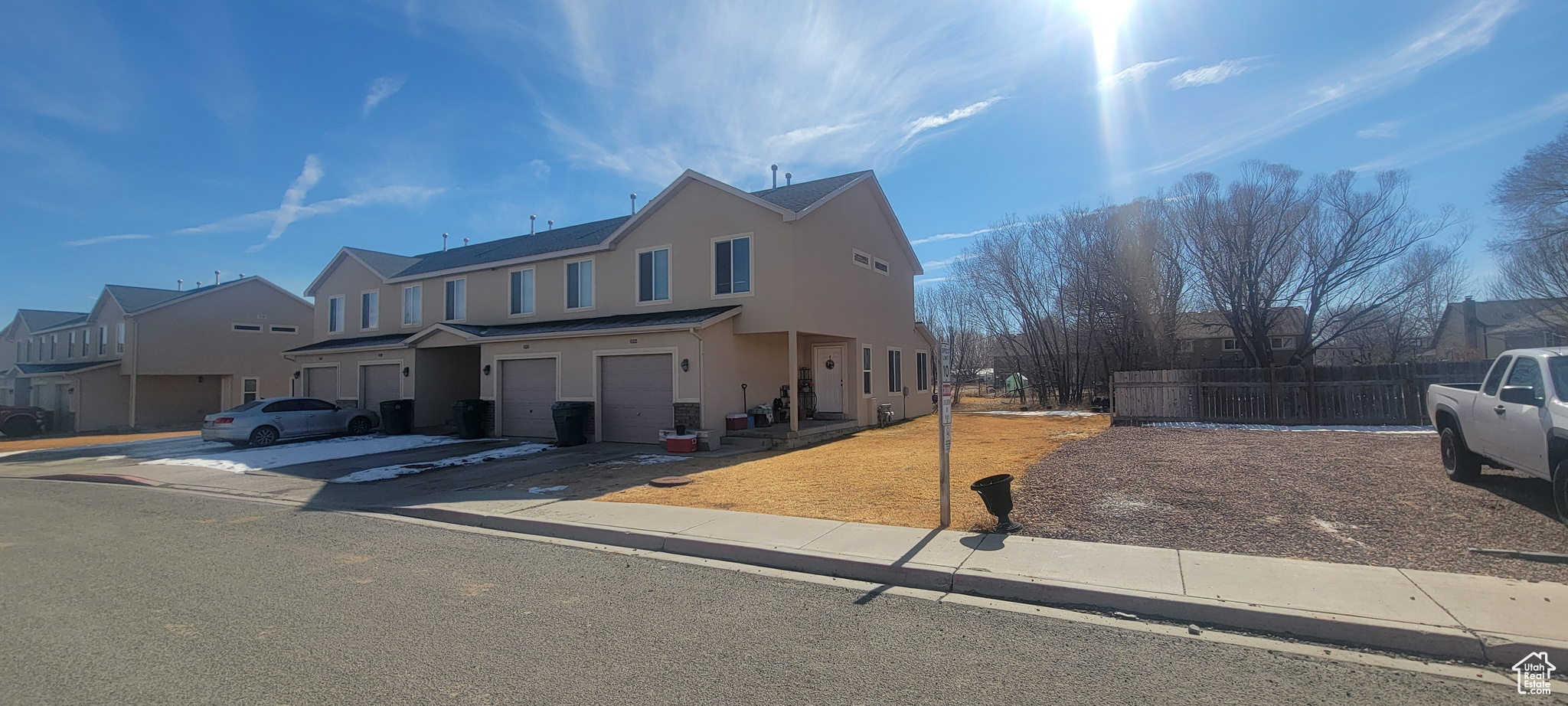 View of front of property with stucco siding, an attached garage, fence, a residential view, and driveway