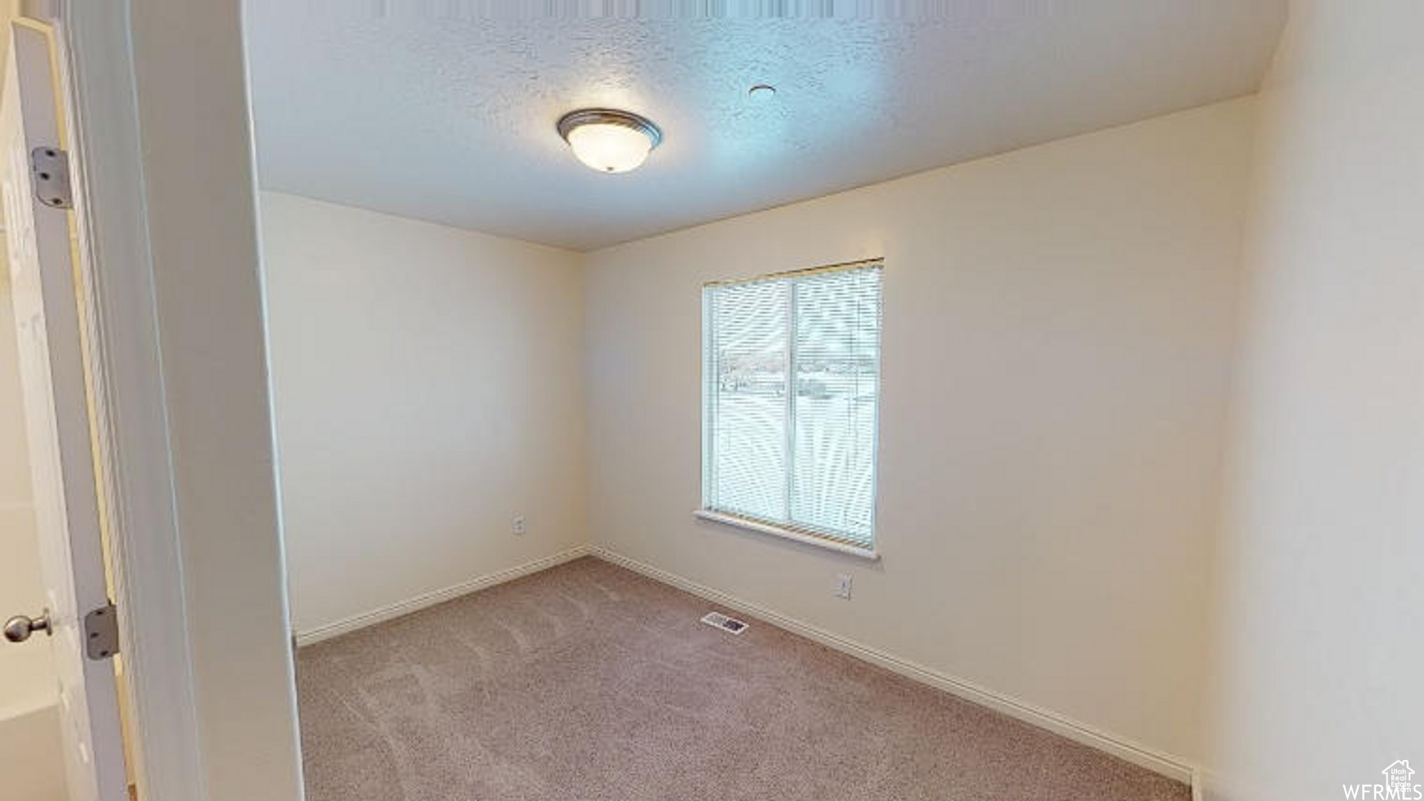 Spare room featuring a textured ceiling, baseboards, visible vents, and light colored carpet