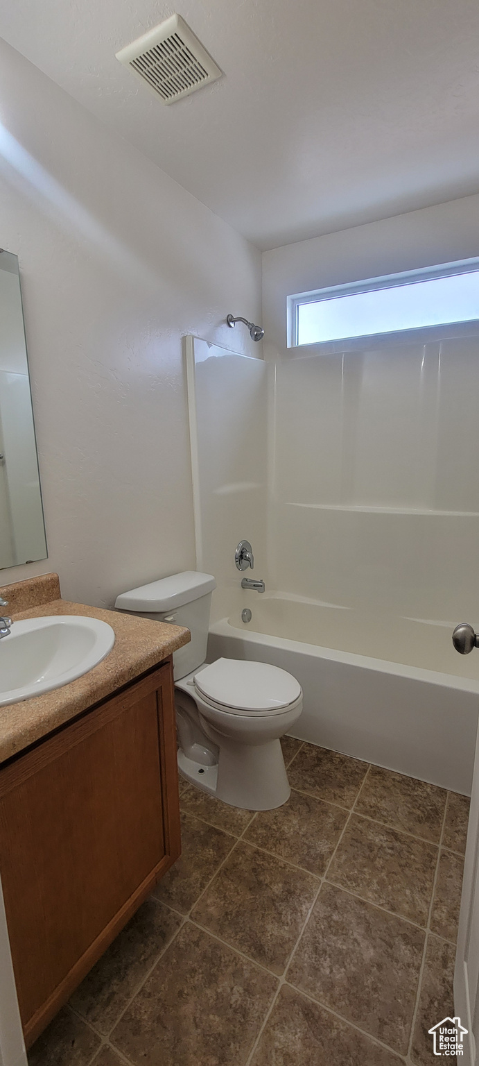 Bathroom featuring tile patterned flooring, toilet, vanity, visible vents, and  shower combination