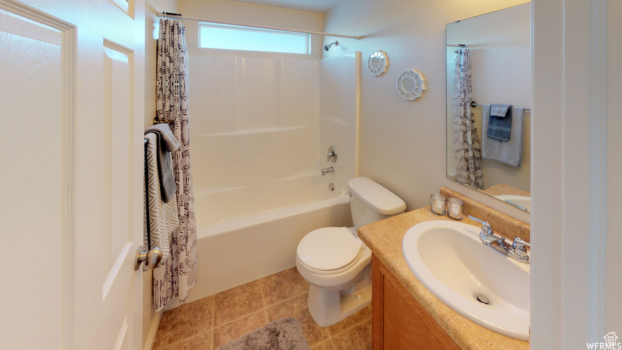 Full bathroom featuring toilet, tile patterned floors, shower / bath combination with curtain, and vanity