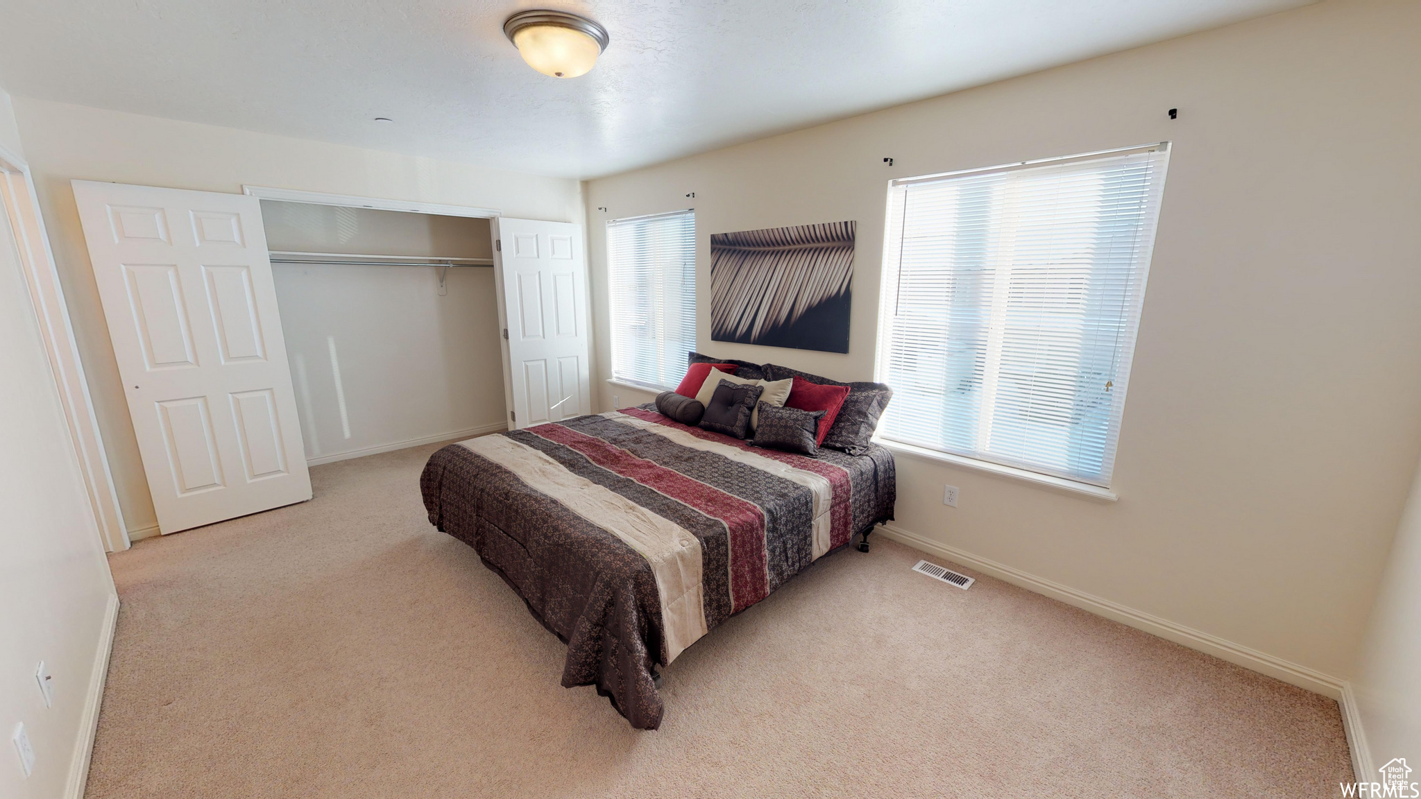 Bedroom featuring visible vents, light carpet, and multiple windows