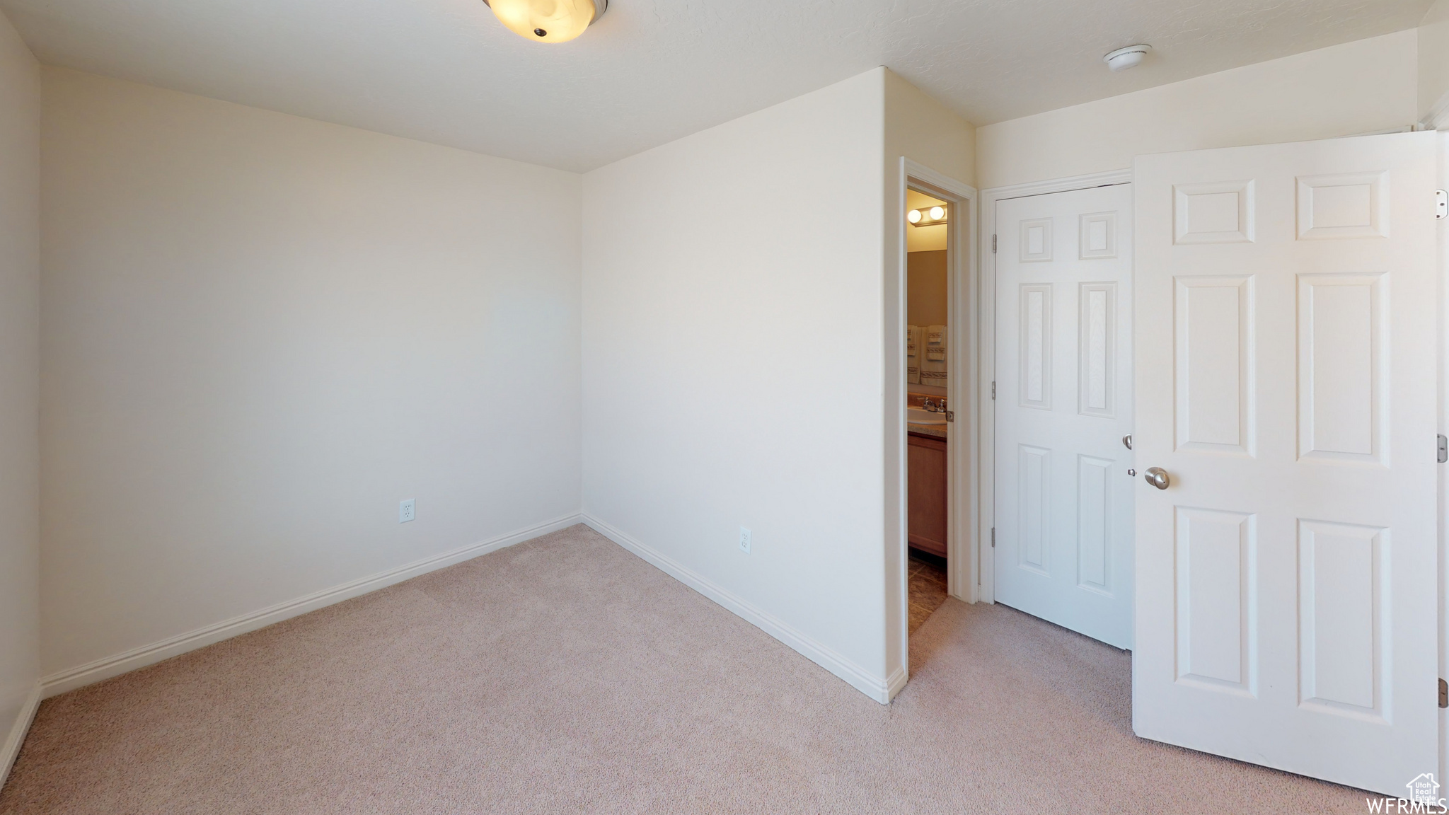 Unfurnished bedroom with light carpet, a closet, and baseboards