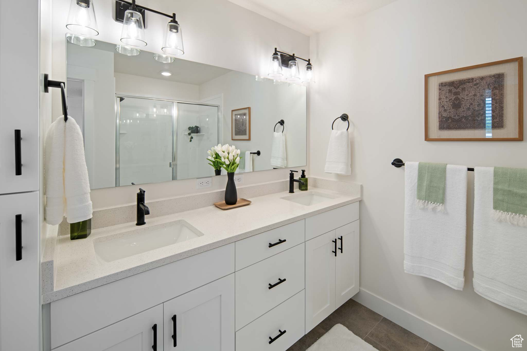 Bathroom with a shower stall, double vanity, a sink, and tile patterned floors