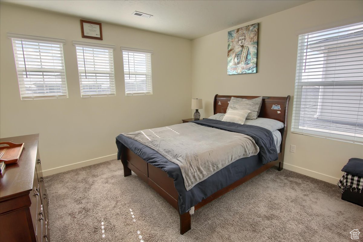 Bedroom with light carpet, visible vents, and baseboards