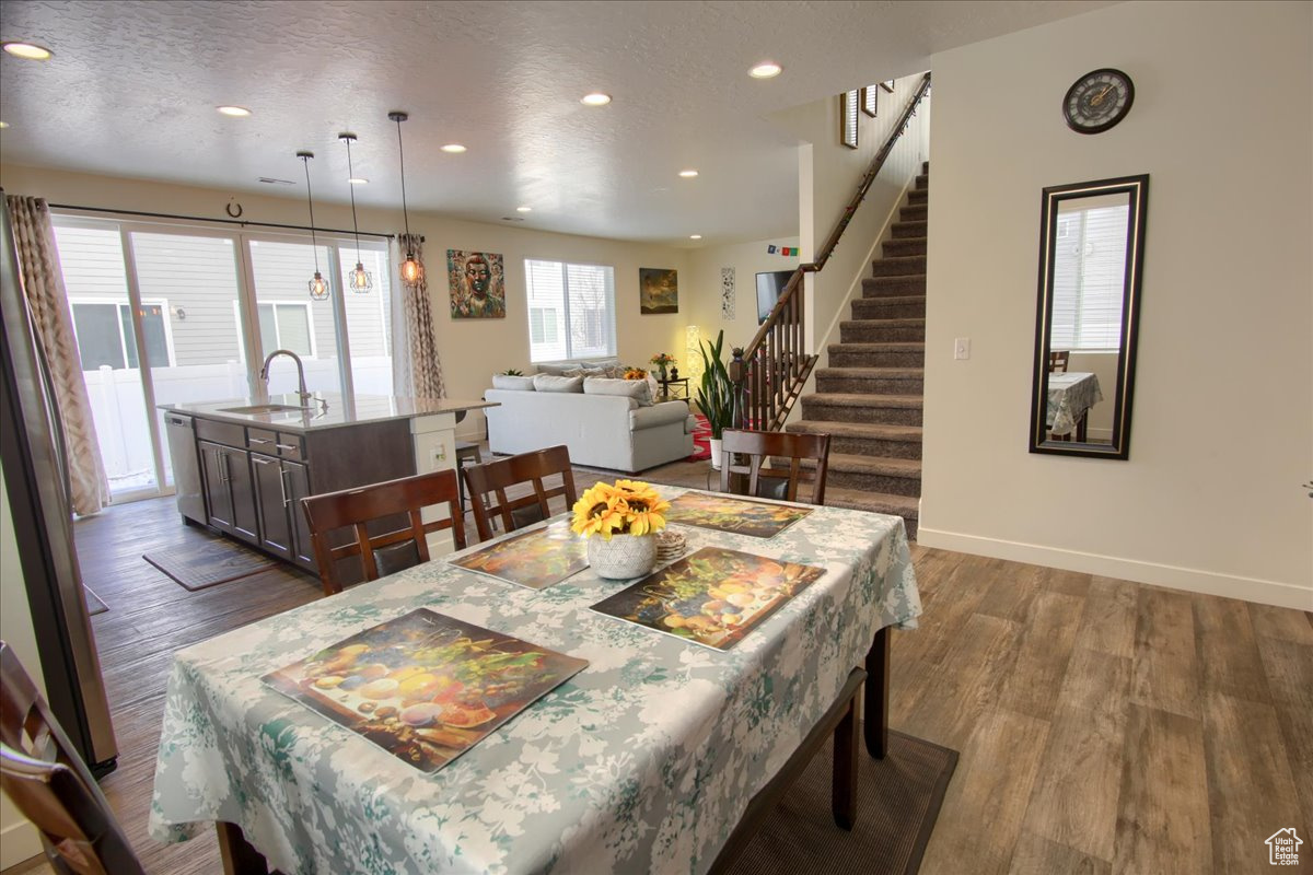 Dining room featuring dark wood-style floors, stairway, and a textured ceiling