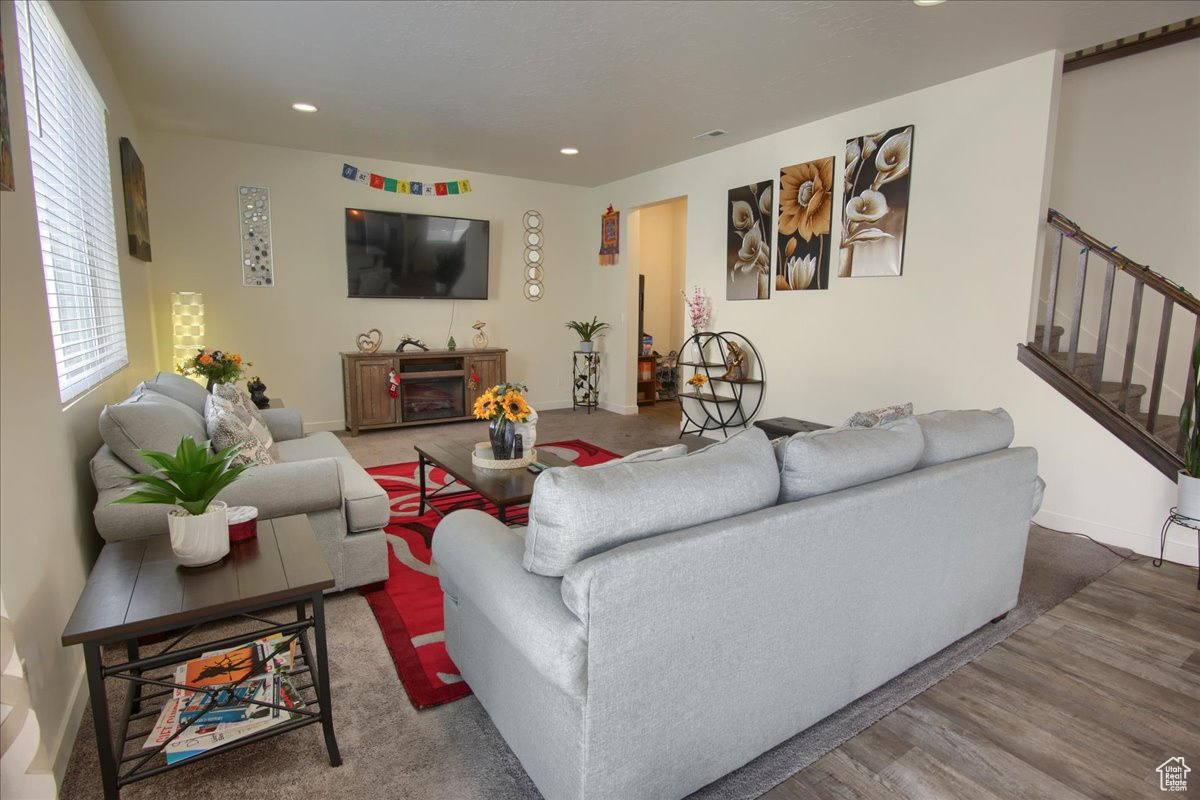 Living room with stairs, baseboards, wood finished floors, and recessed lighting