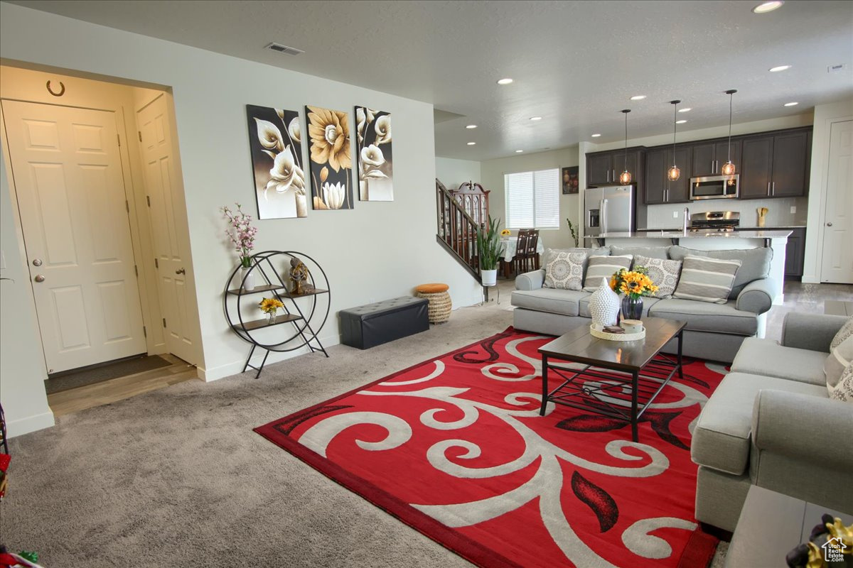 Living area featuring baseboards, visible vents, stairs, carpet floors, and recessed lighting