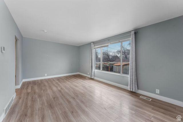 Spare room featuring light wood-style flooring, visible vents, and baseboards