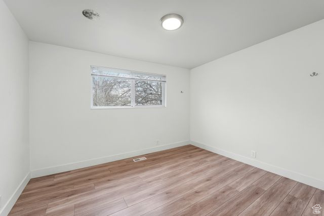 Empty room featuring baseboards, visible vents, and light wood finished floors