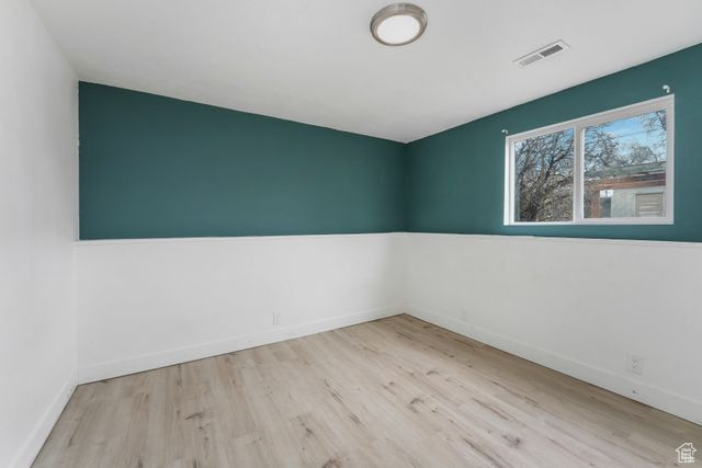 Empty room featuring baseboards, visible vents, and light wood-style floors