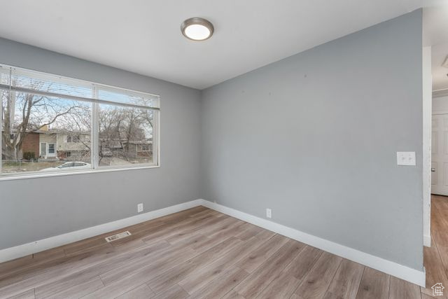 Unfurnished room featuring visible vents, light wood finished floors, and baseboards