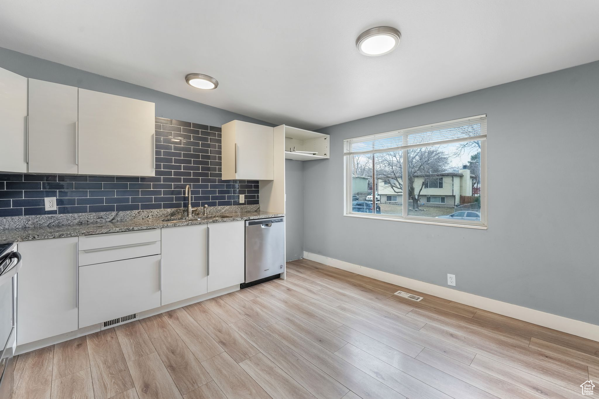 Kitchen featuring stone counters, a sink, visible vents, stainless steel dishwasher, and tasteful backsplash