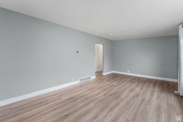 Unfurnished room featuring visible vents, light wood finished floors, and baseboards