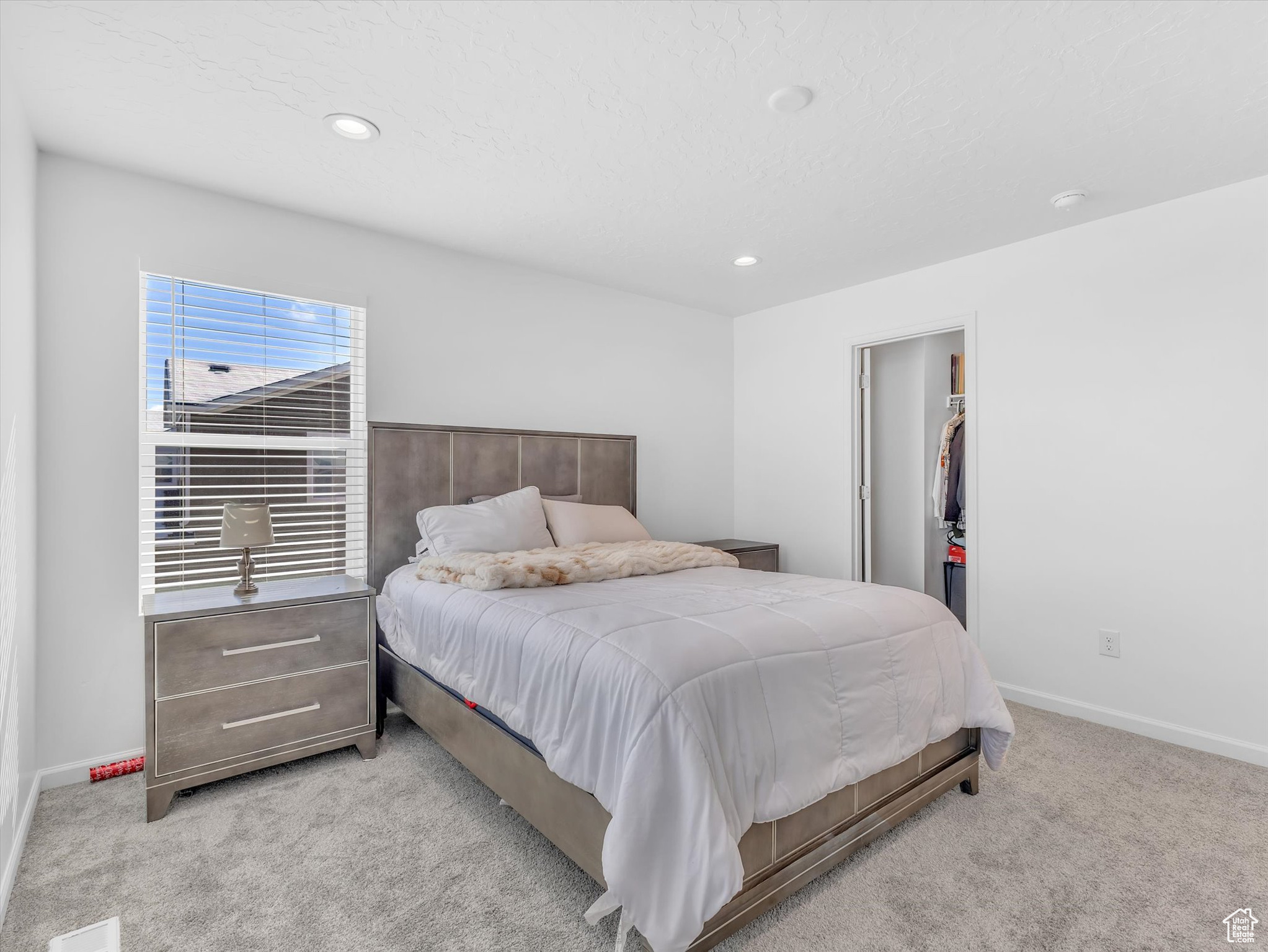 Bedroom with baseboards, light colored carpet, a walk in closet, a closet, and recessed lighting