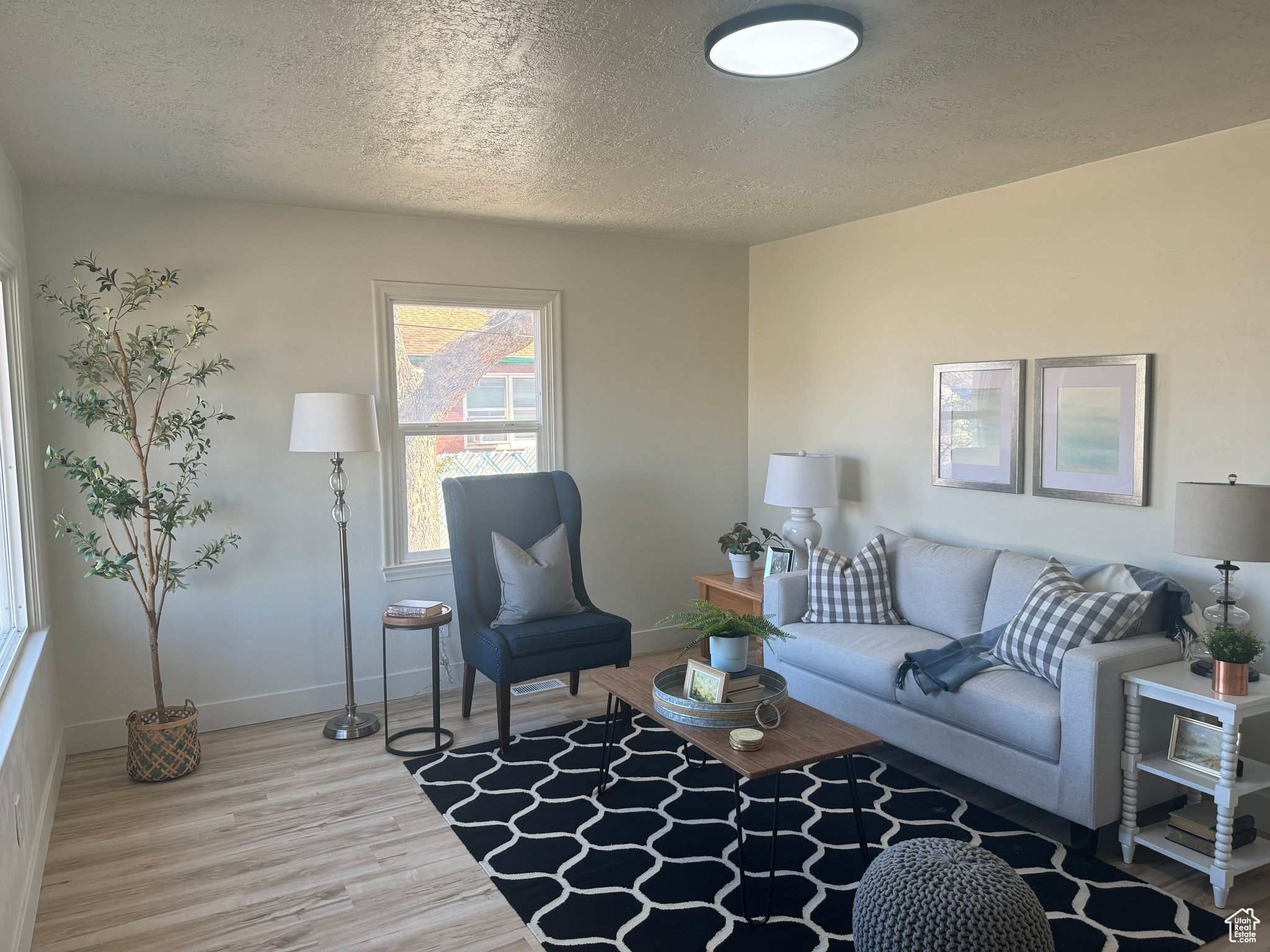 Living room with a textured ceiling, baseboards, and wood finished floors