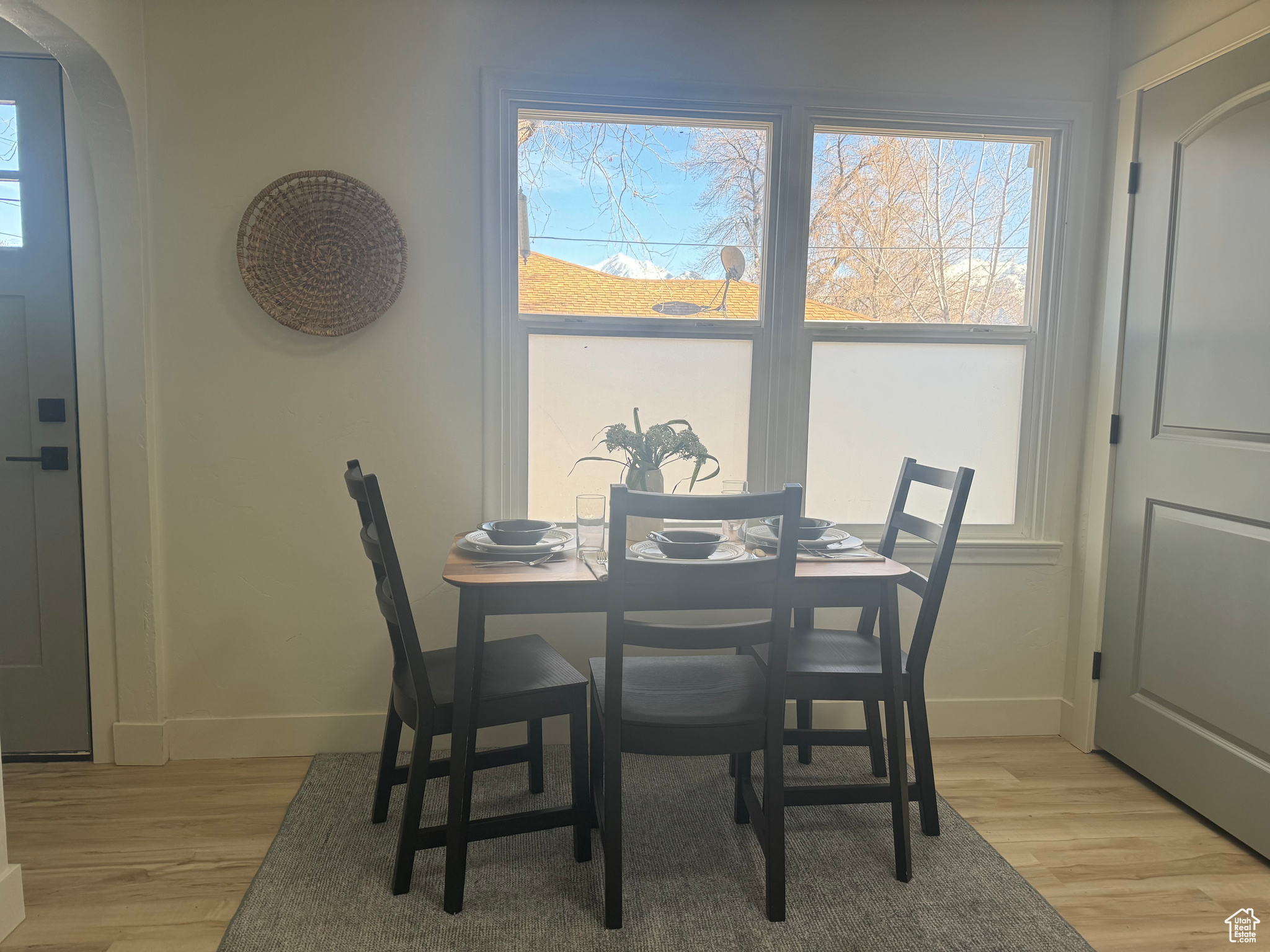 Dining space with light wood-style flooring, arched walkways, and baseboards