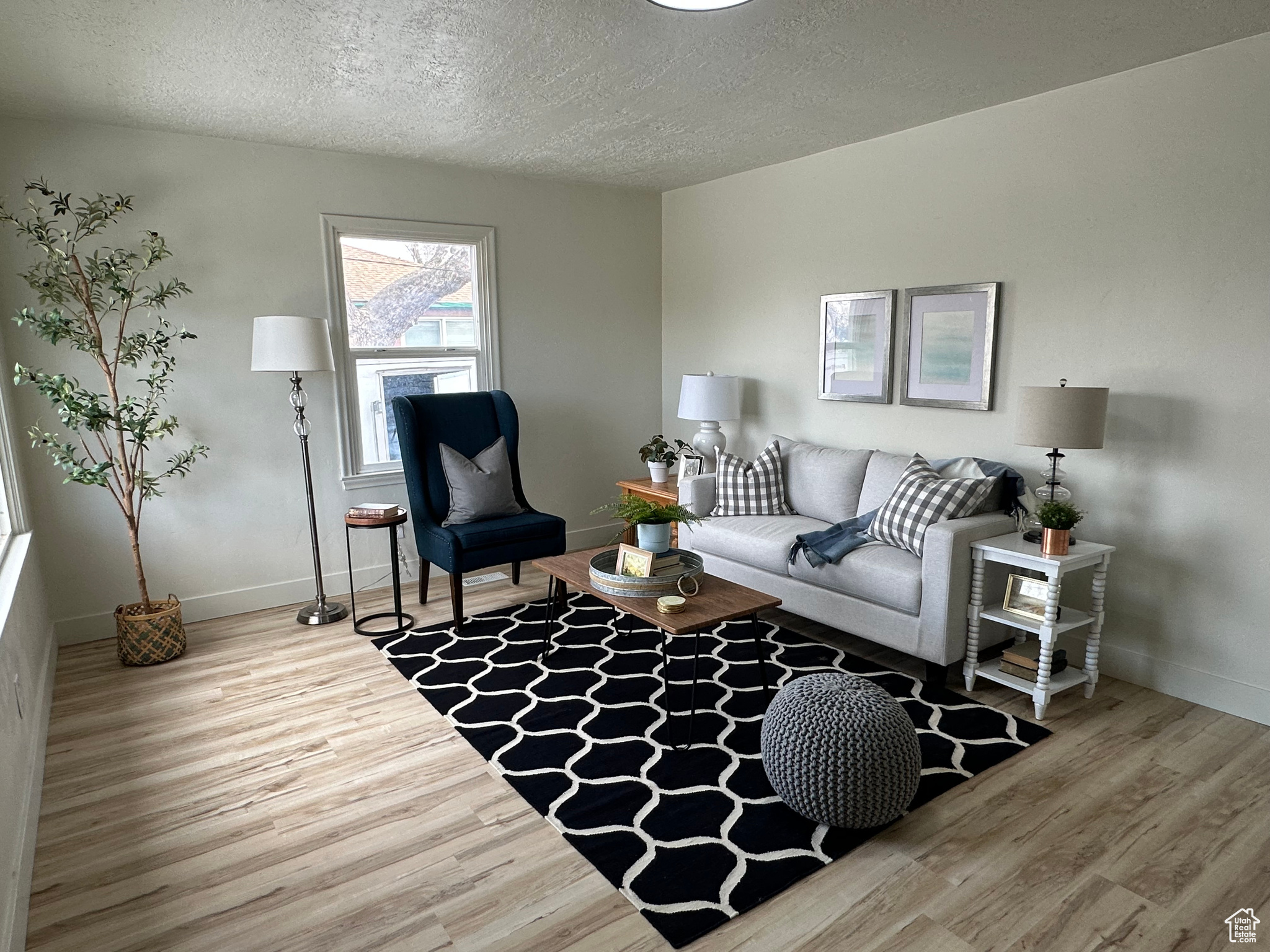 Living area featuring a textured ceiling, wood finished floors, and baseboards
