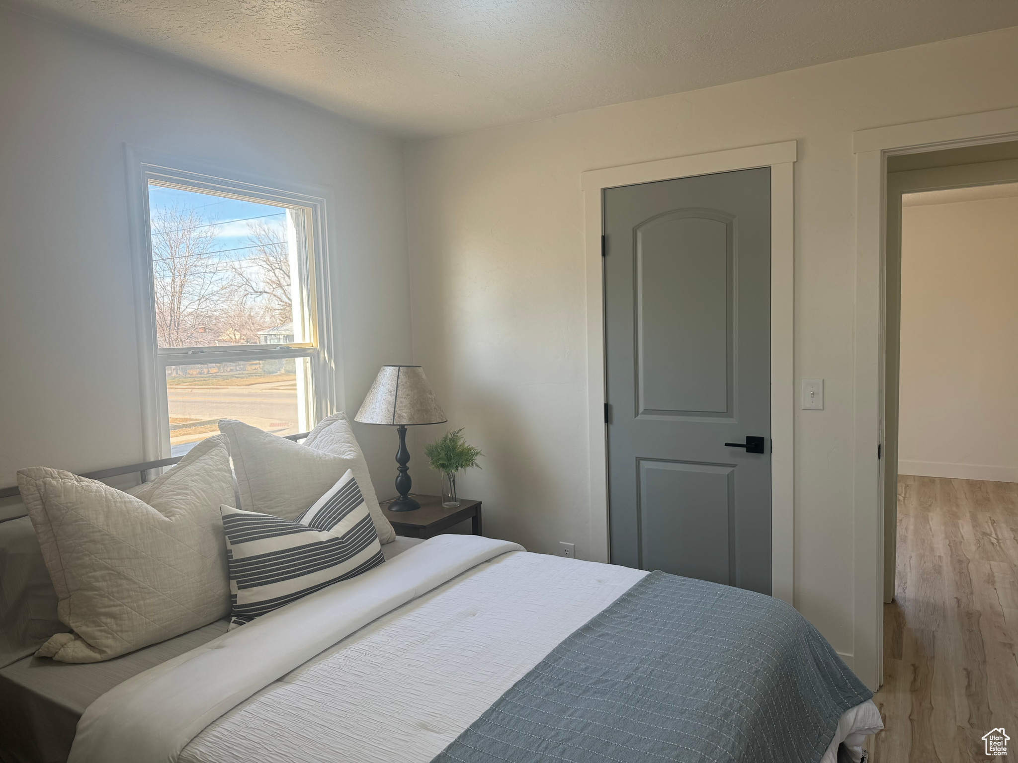 Bedroom with baseboards, light wood-style flooring, and a textured ceiling