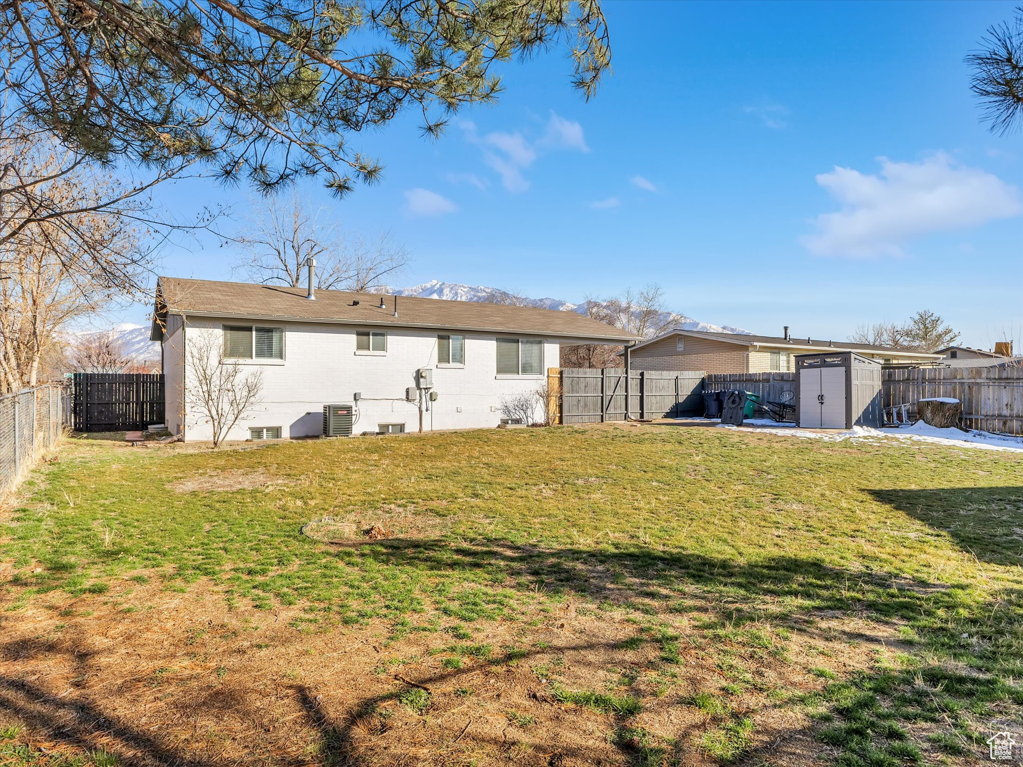 Back of property with a yard, a fenced backyard, an outdoor structure, and a storage unit