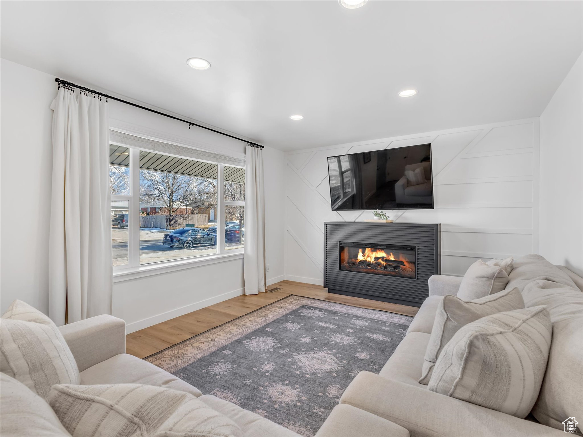 Living area featuring a glass covered fireplace, baseboards, recessed lighting, and wood finished floors