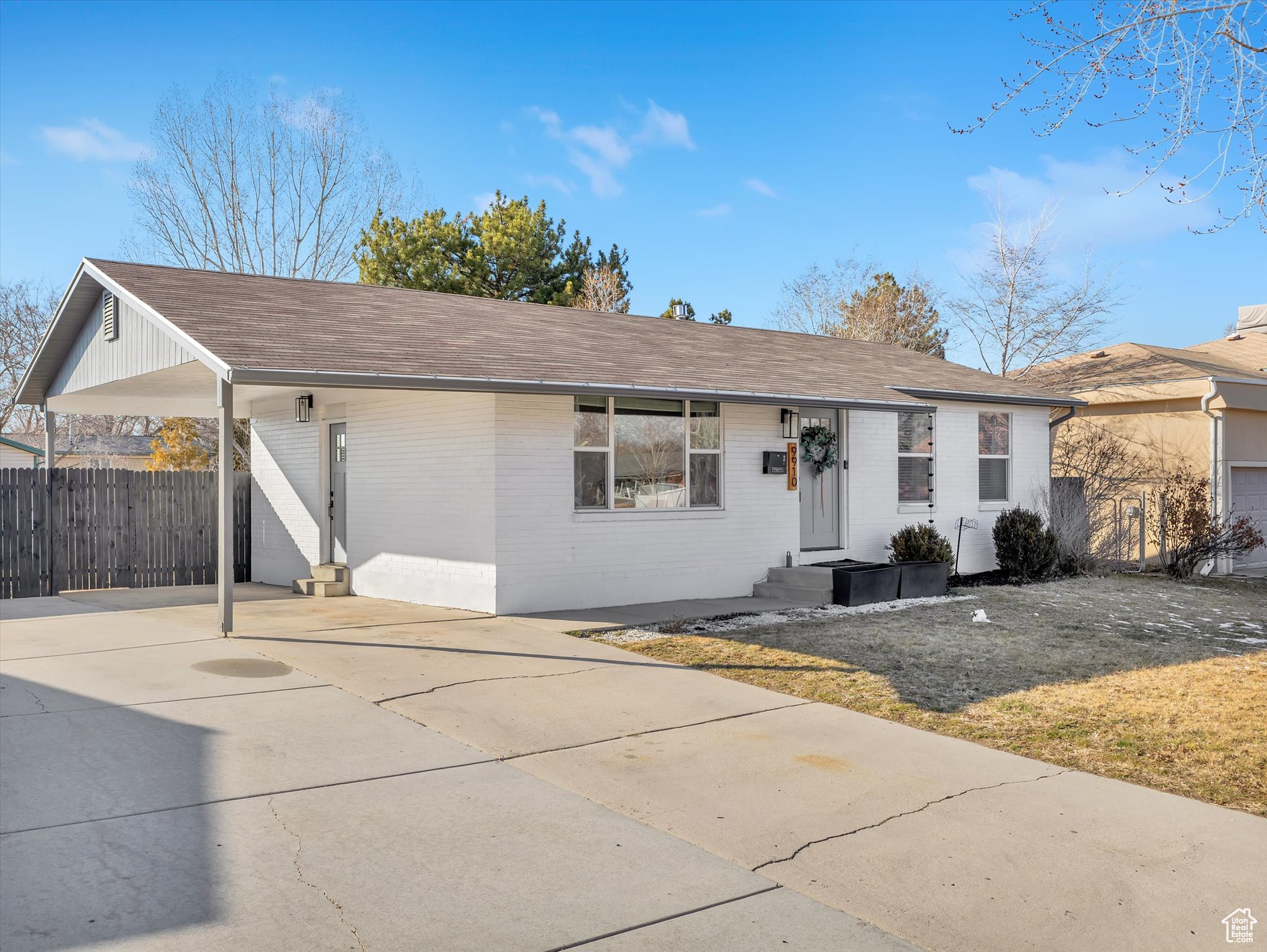 Ranch-style home with concrete driveway, fence, a front lawn, a carport, and brick siding