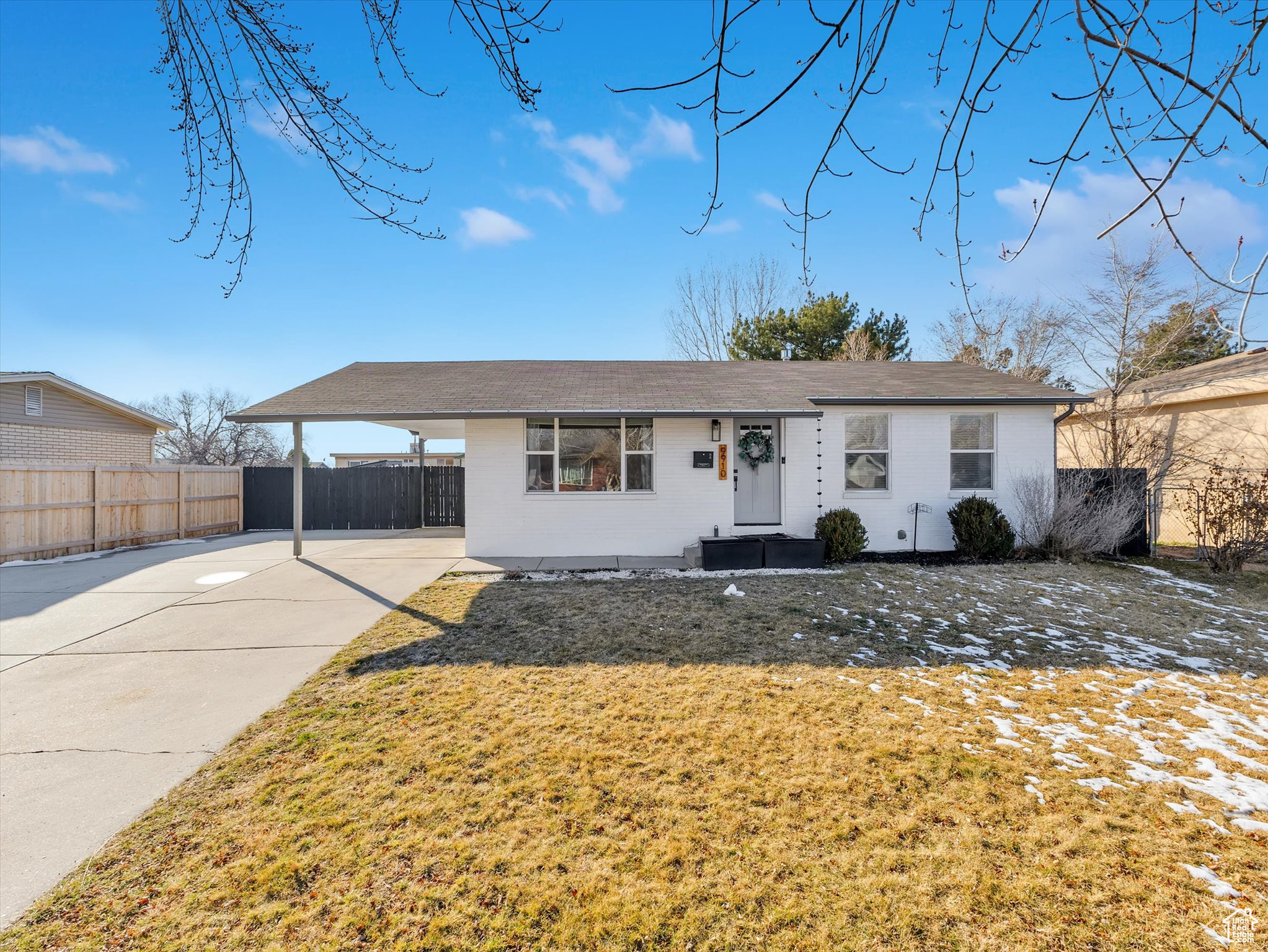 Ranch-style house featuring concrete driveway, fence, a front yard, a carport, and brick siding
