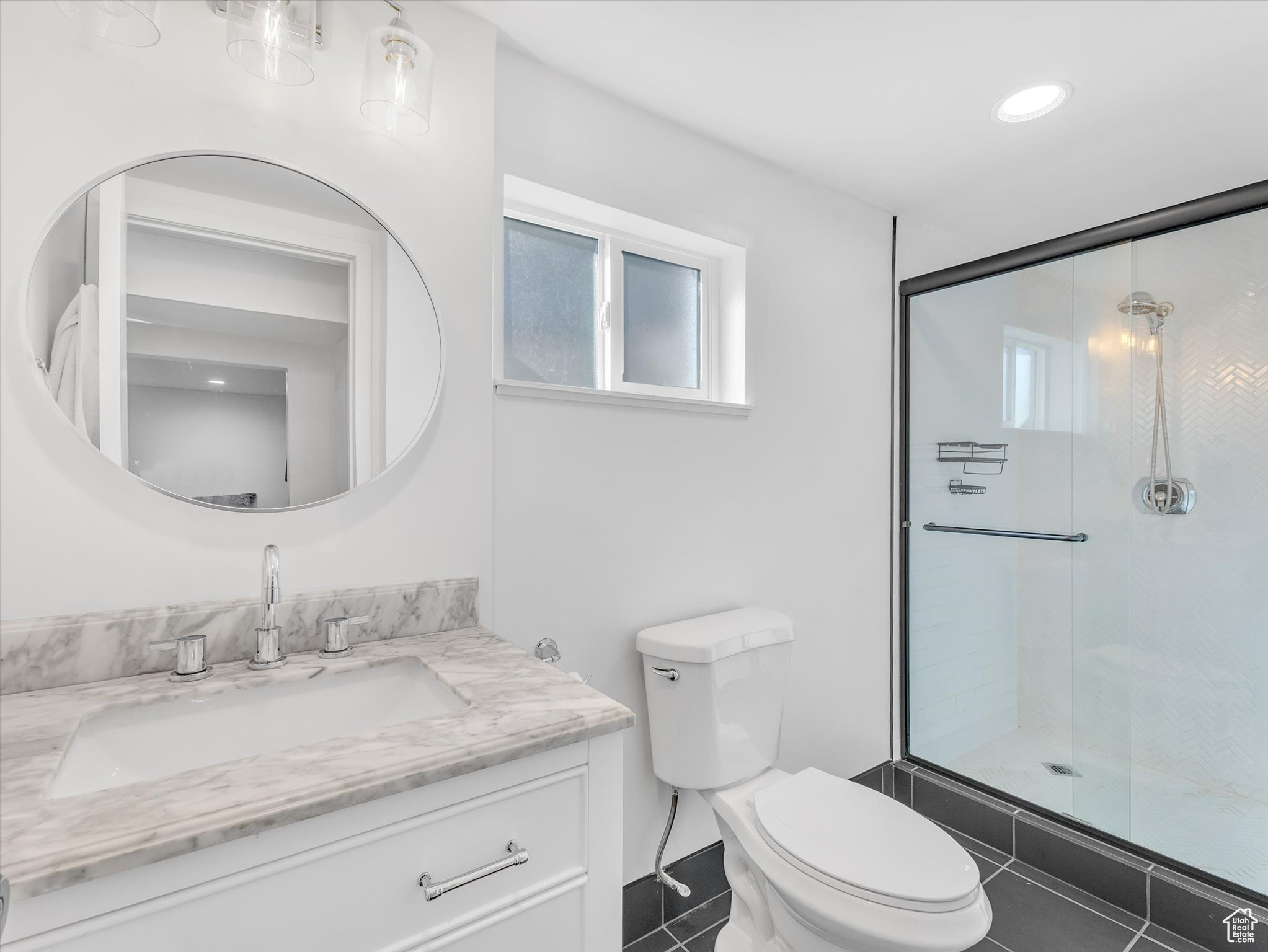 Bathroom featuring toilet, tile patterned floors, vanity, and a shower with shower door