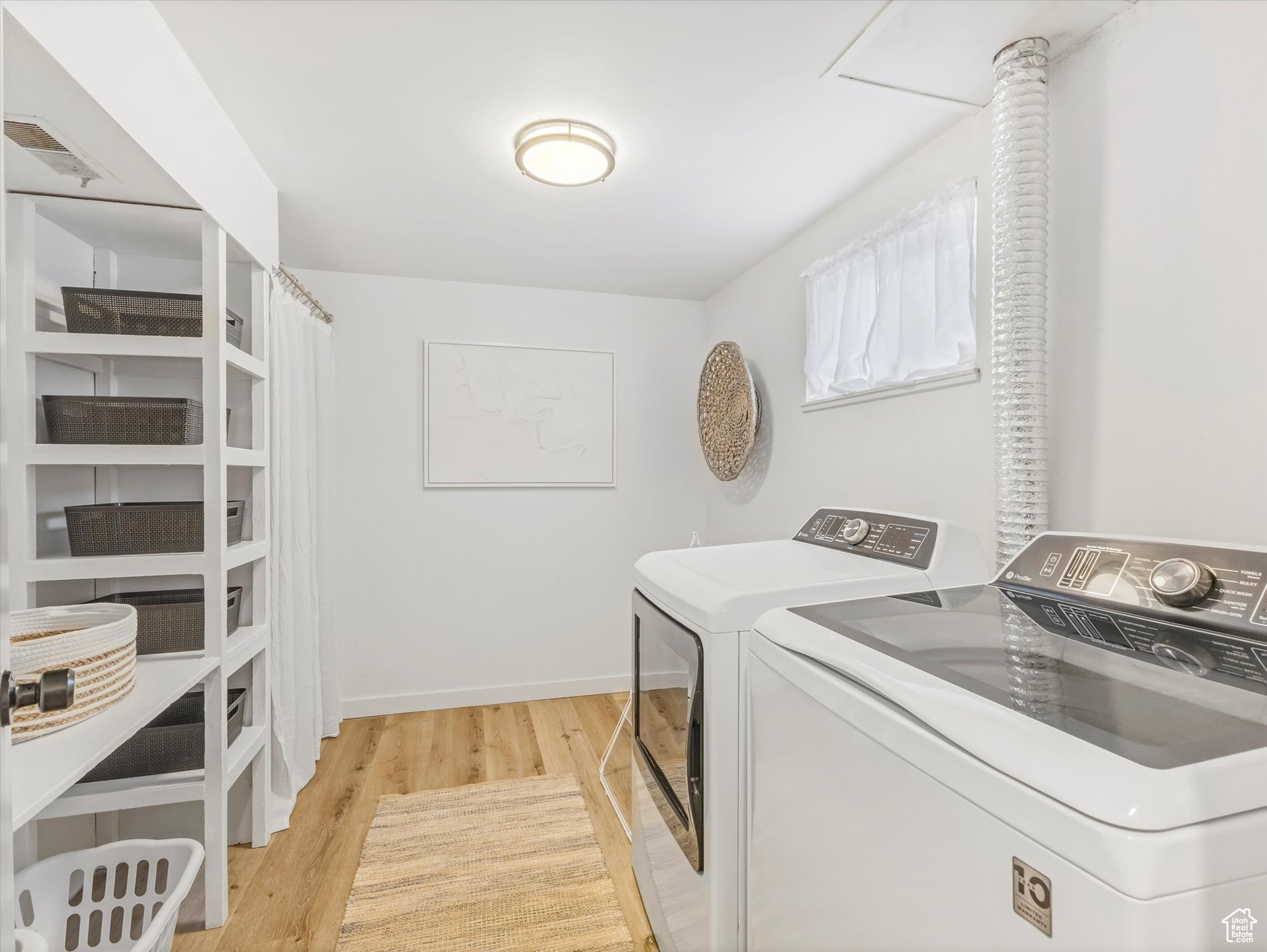Clothes washing area with baseboards, visible vents, washing machine and clothes dryer, laundry area, and light wood-type flooring