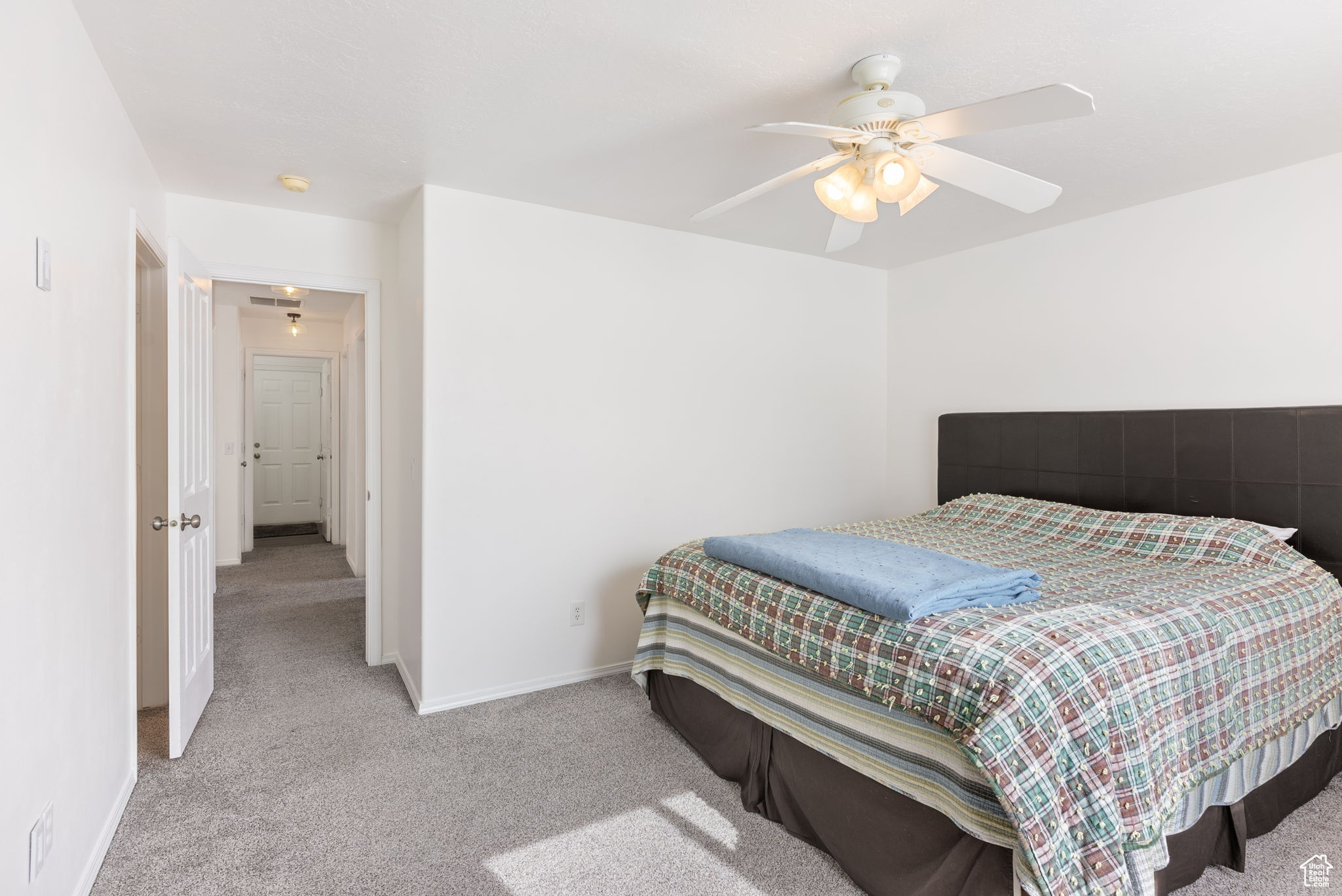 Bedroom with a ceiling fan, light carpet, and baseboards