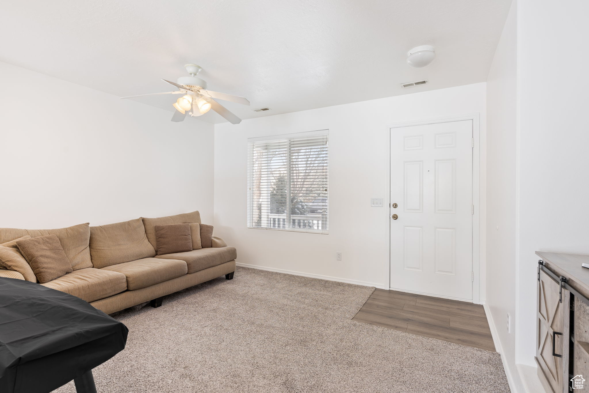 Living room with light colored carpet, visible vents, ceiling fan, and baseboards