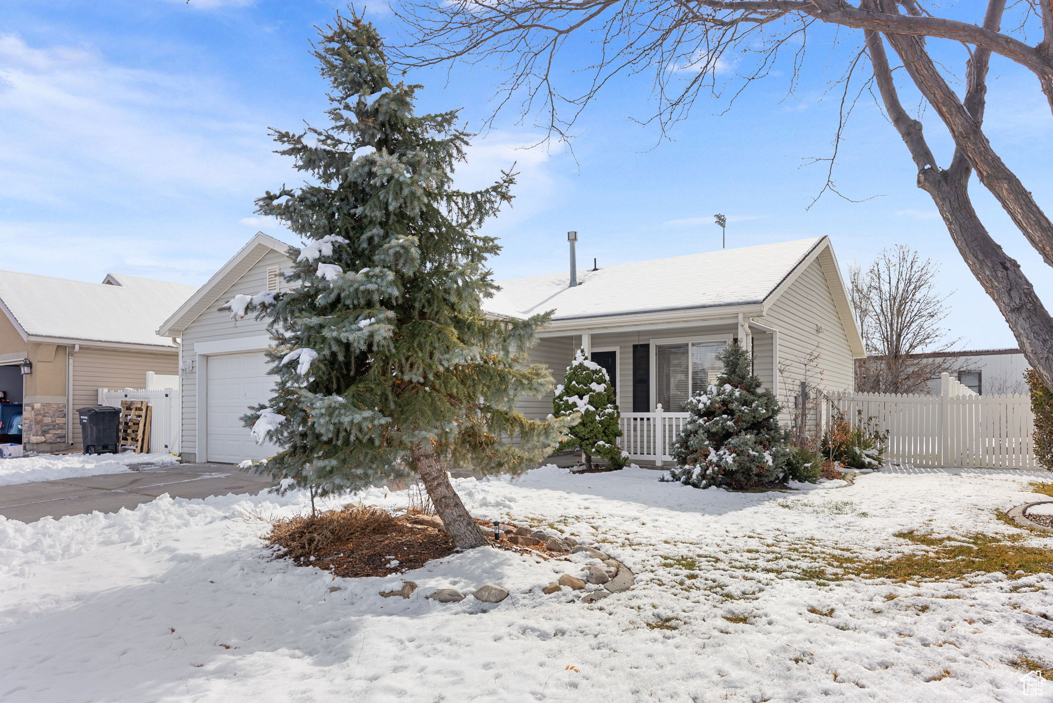 View of front of house with a garage, covered porch, and fence