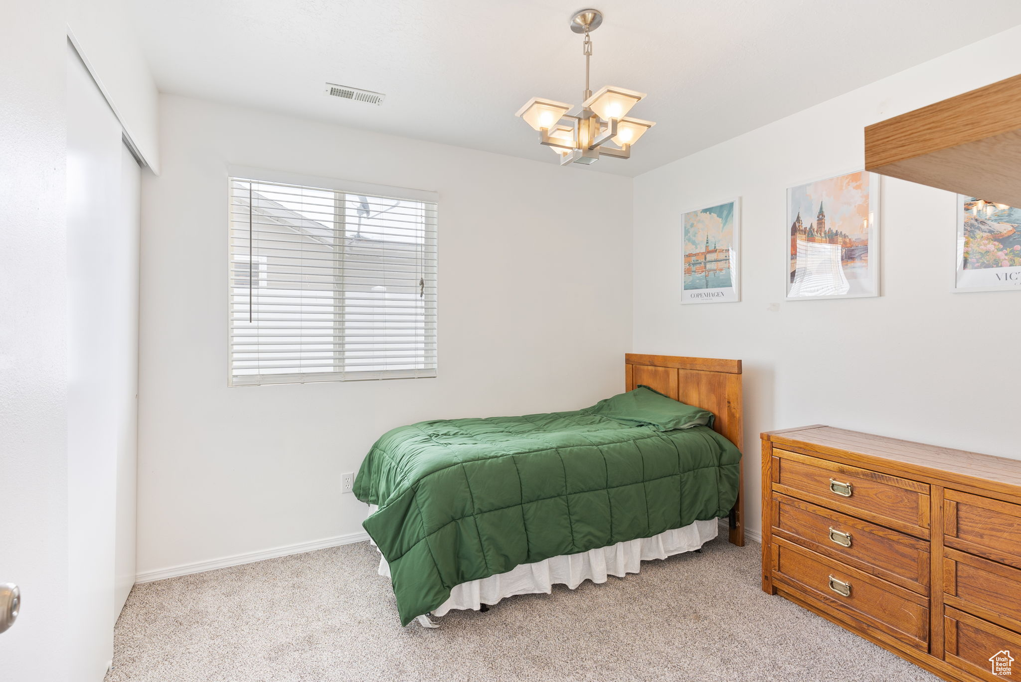 Bedroom with baseboards, visible vents, a chandelier, and light colored carpet
