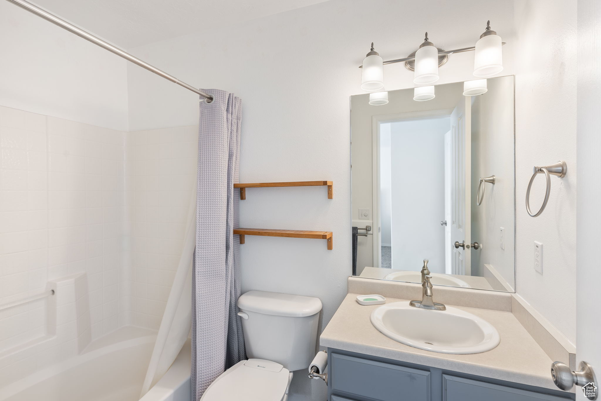 Bathroom with shower / bath combination with curtain, vanity, and toilet