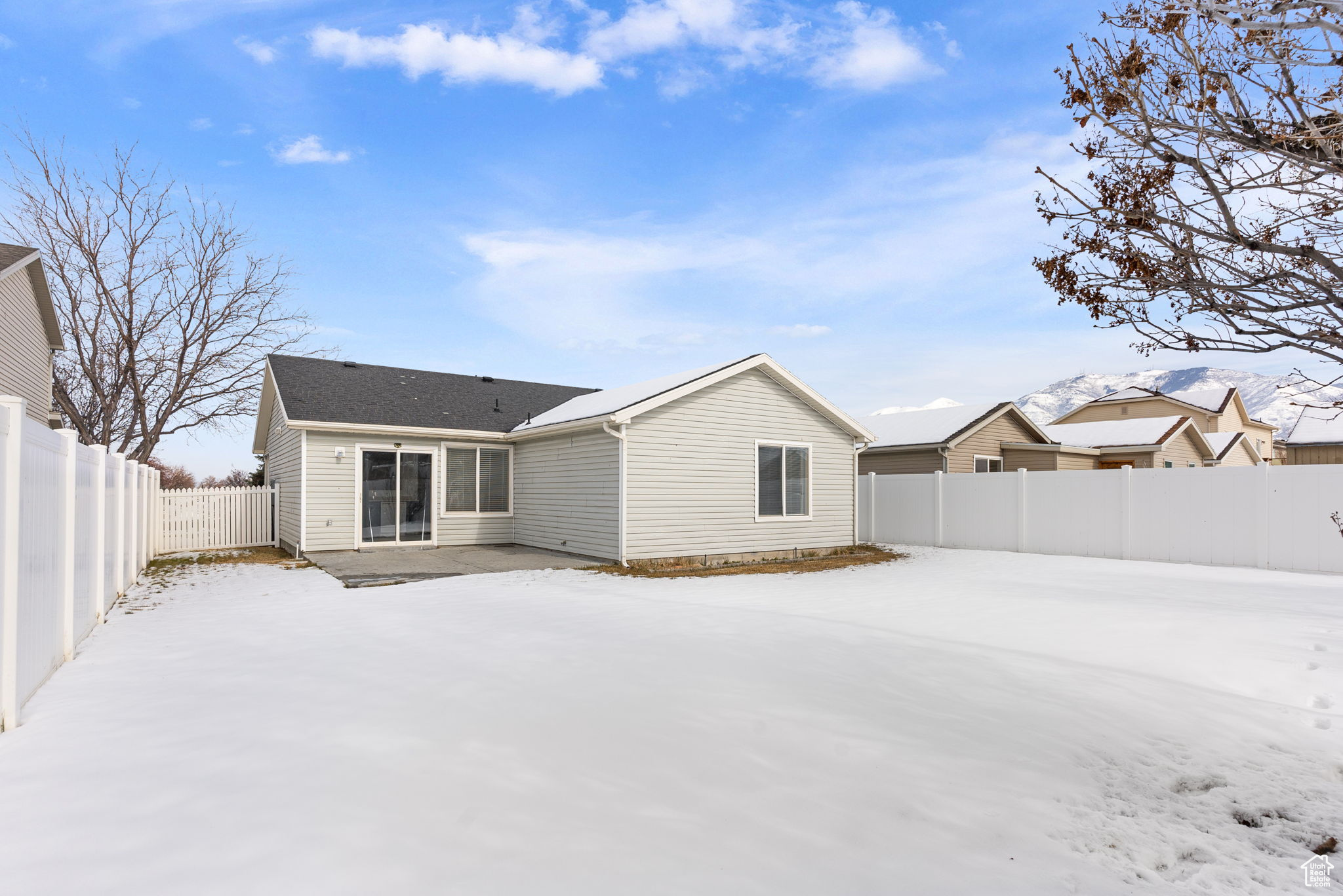 Snow covered back of property featuring a fenced backyard