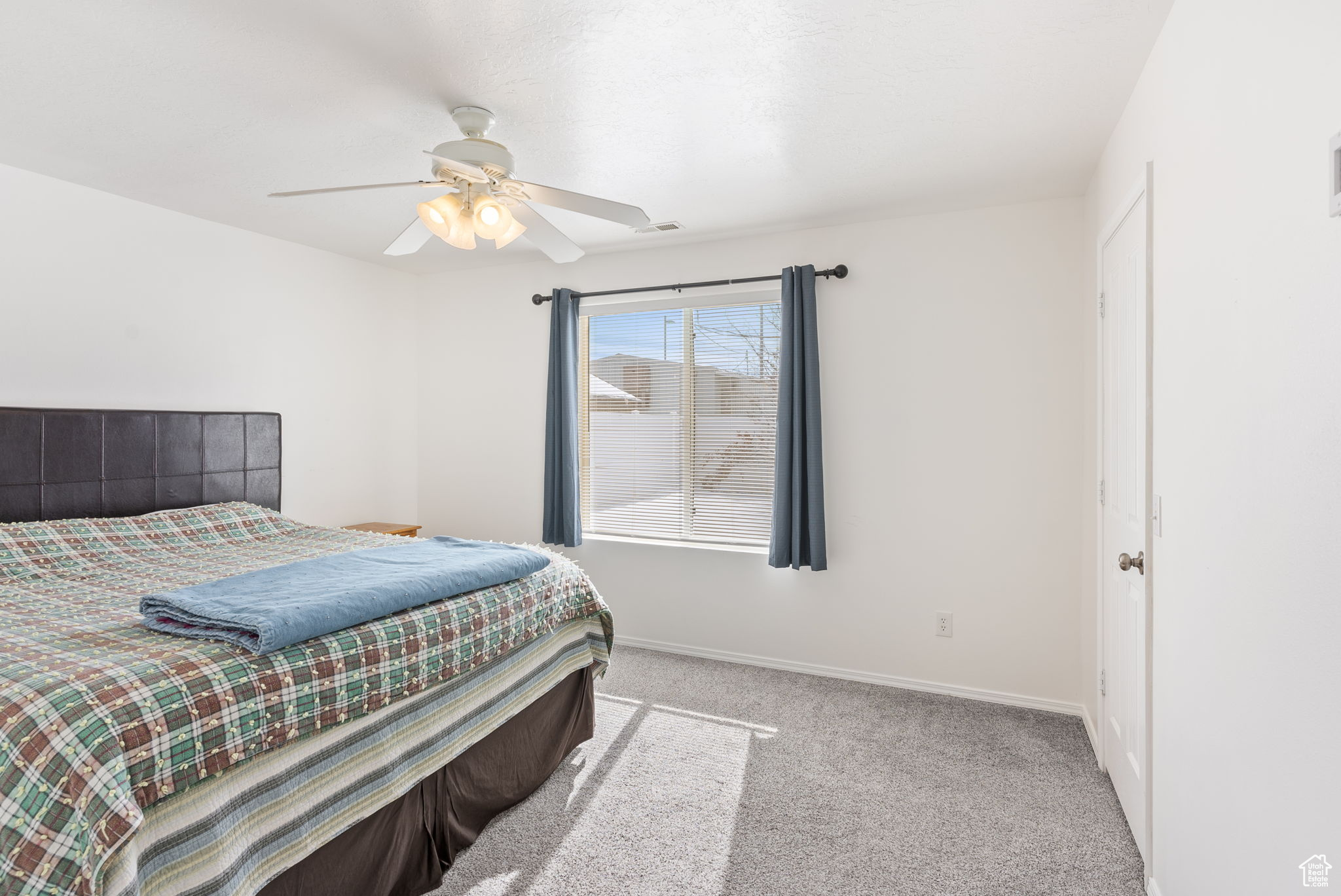 Bedroom with light carpet, ceiling fan, visible vents, and baseboards