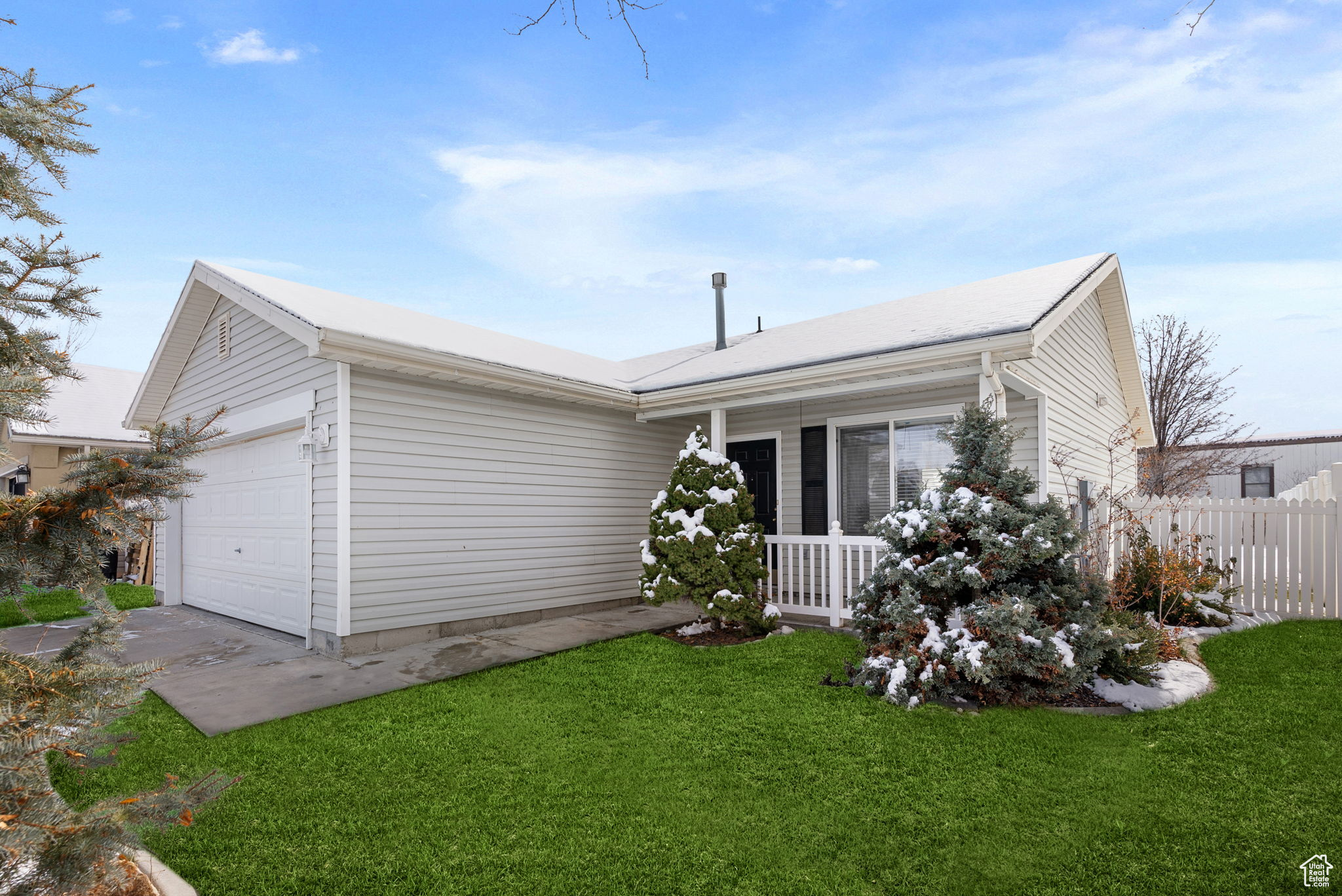 Ranch-style home with a garage, a front lawn, a porch, and fence