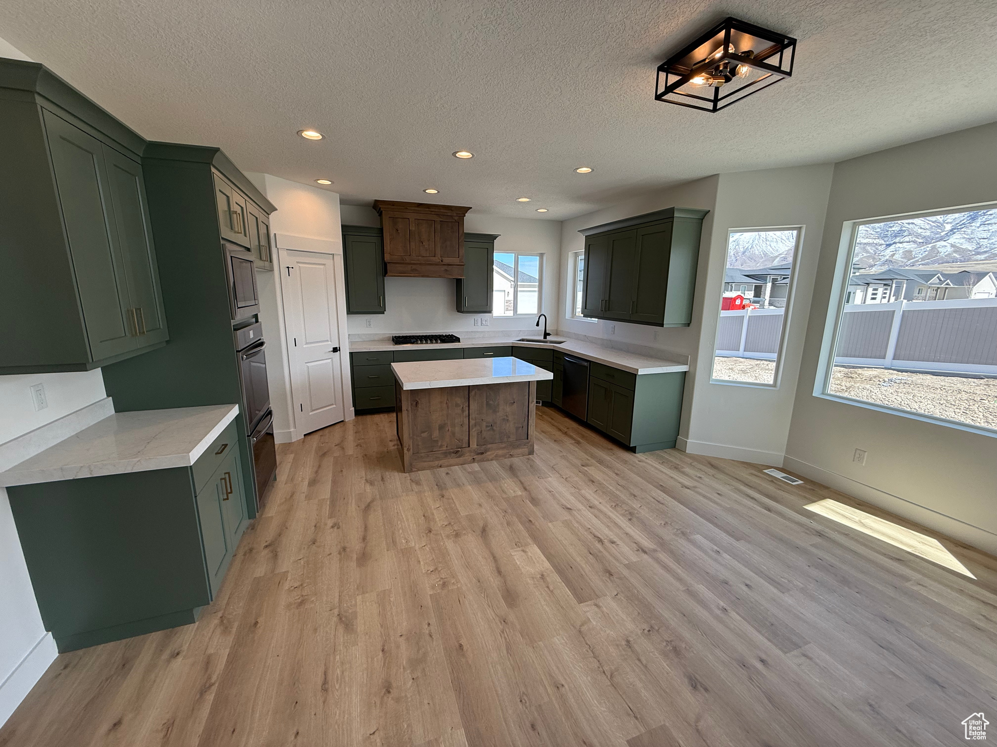Kitchen with light countertops, light wood-style flooring, a kitchen island, and a sink