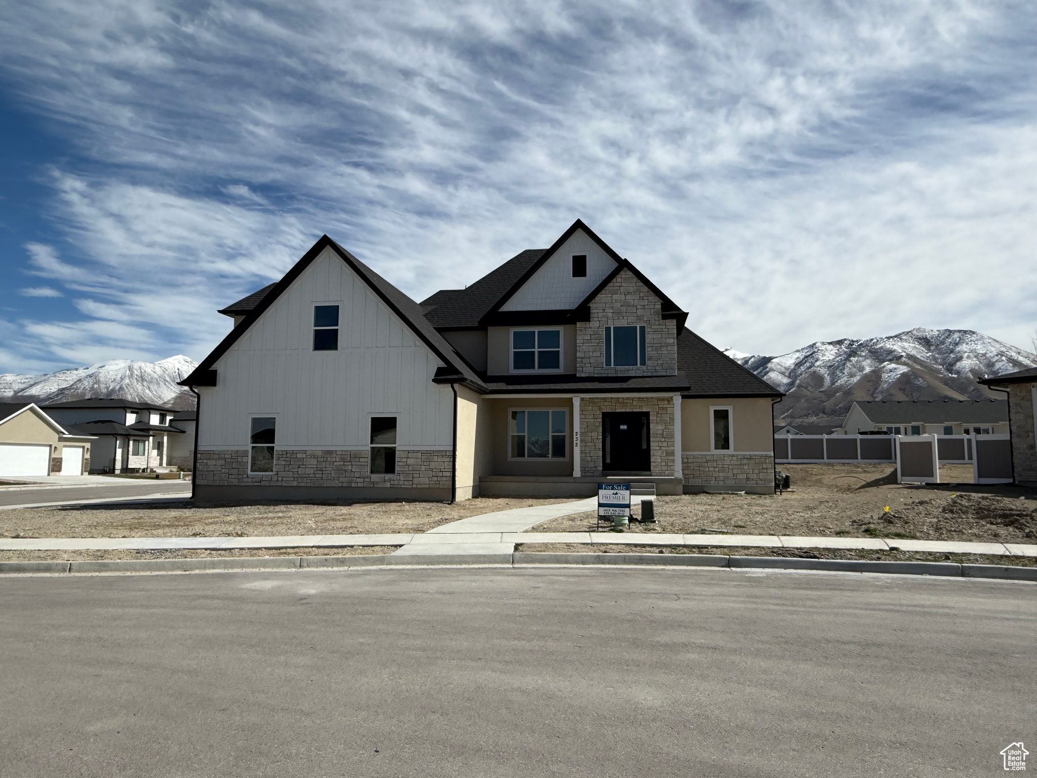 View of front of home with stone siding, a mountain view, and fence