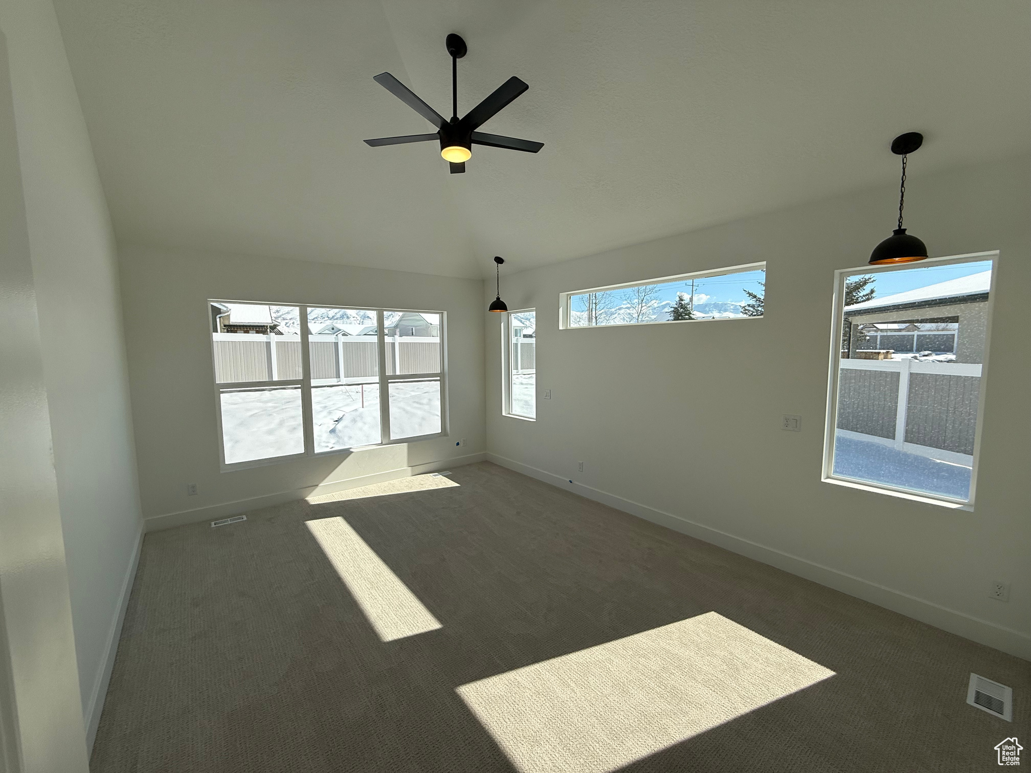 Spare room featuring baseboards, vaulted ceiling, visible vents, and dark colored carpet