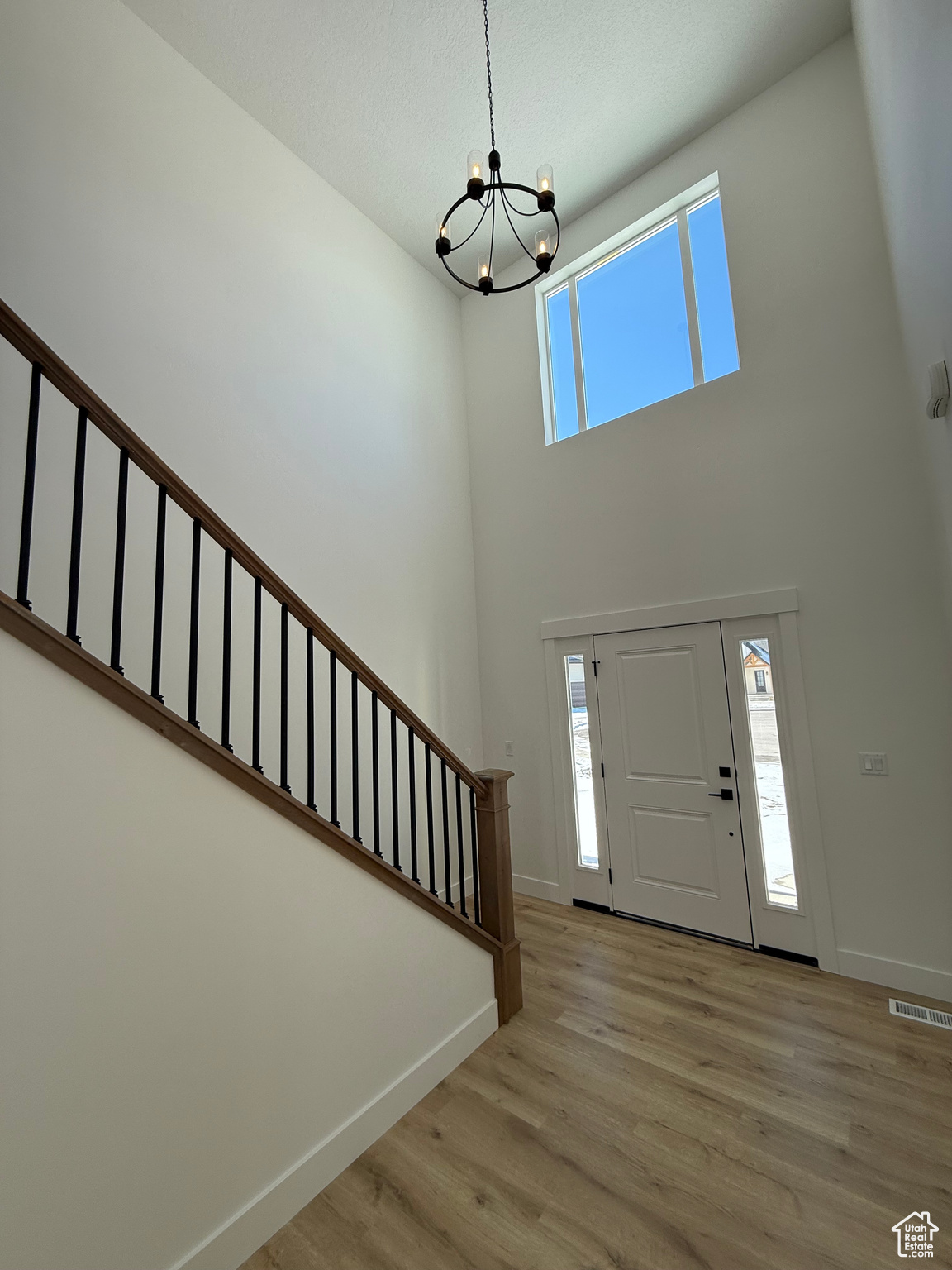 Foyer entrance featuring a chandelier, visible vents, baseboards, stairs, and light wood finished floors
