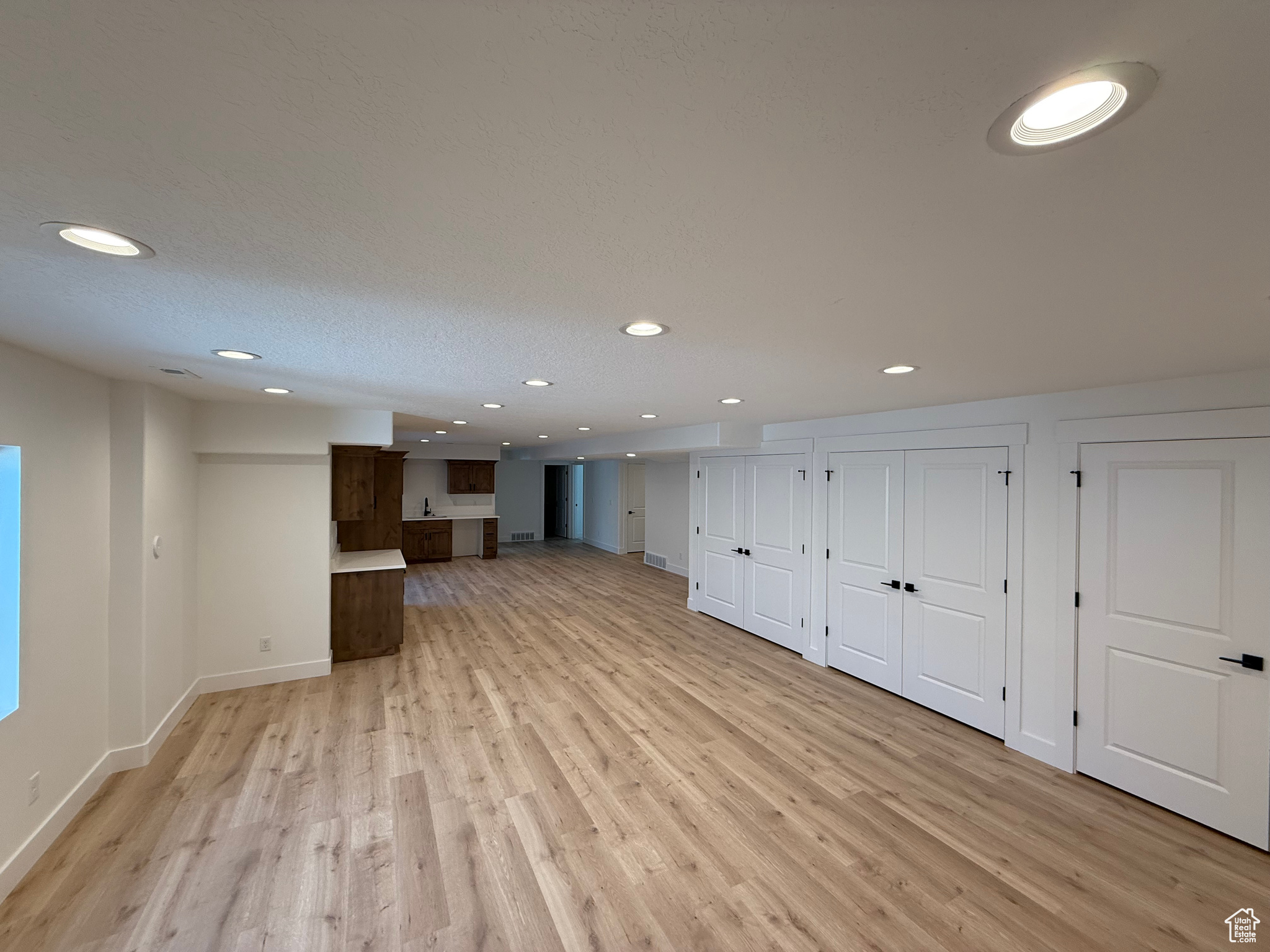 Unfurnished living room with light wood-style floors, recessed lighting, and baseboards
