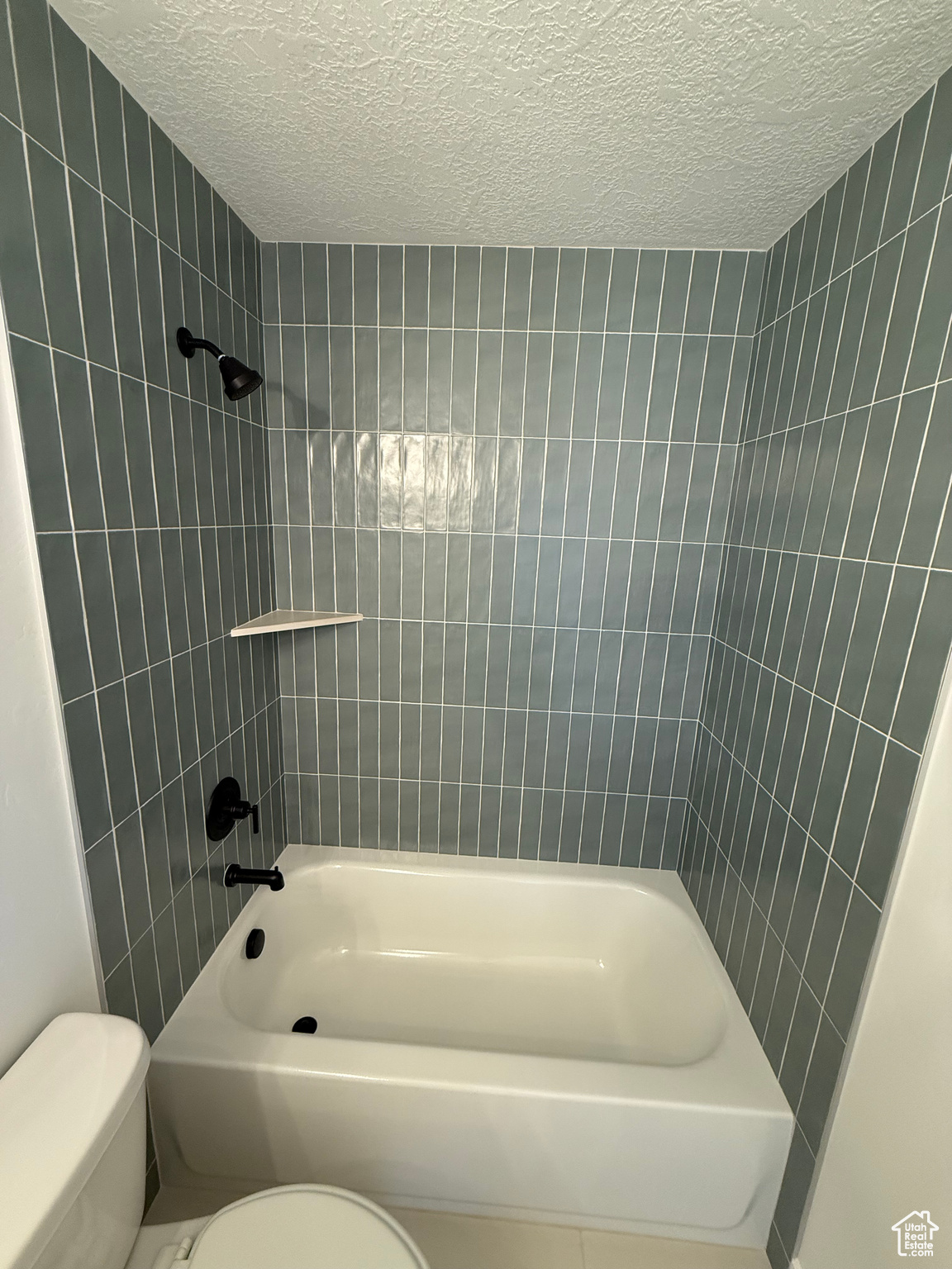 Full bathroom featuring tub / shower combination, a textured ceiling, and toilet