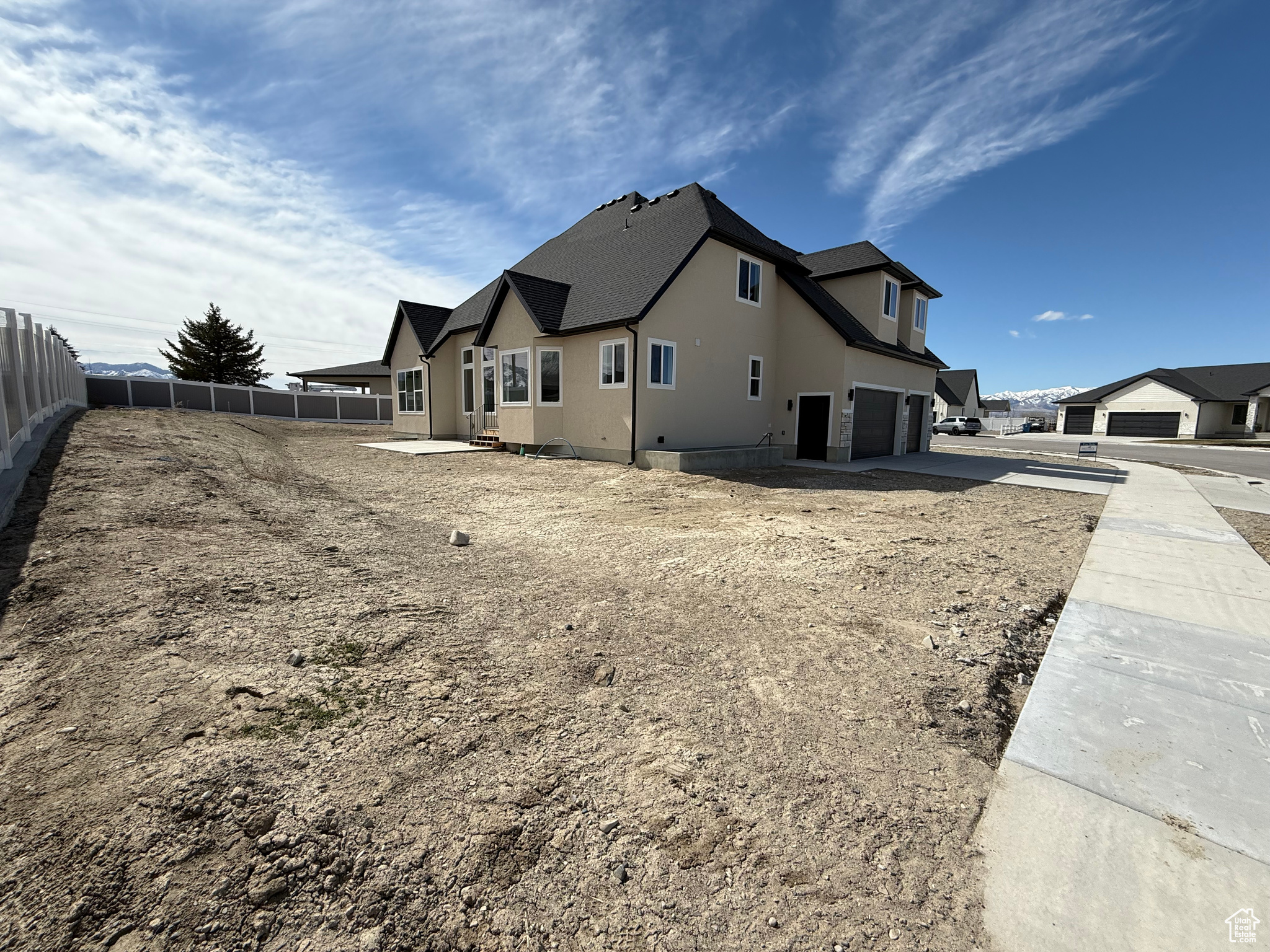 Rear view of property featuring stucco siding, concrete driveway, a garage, and fence