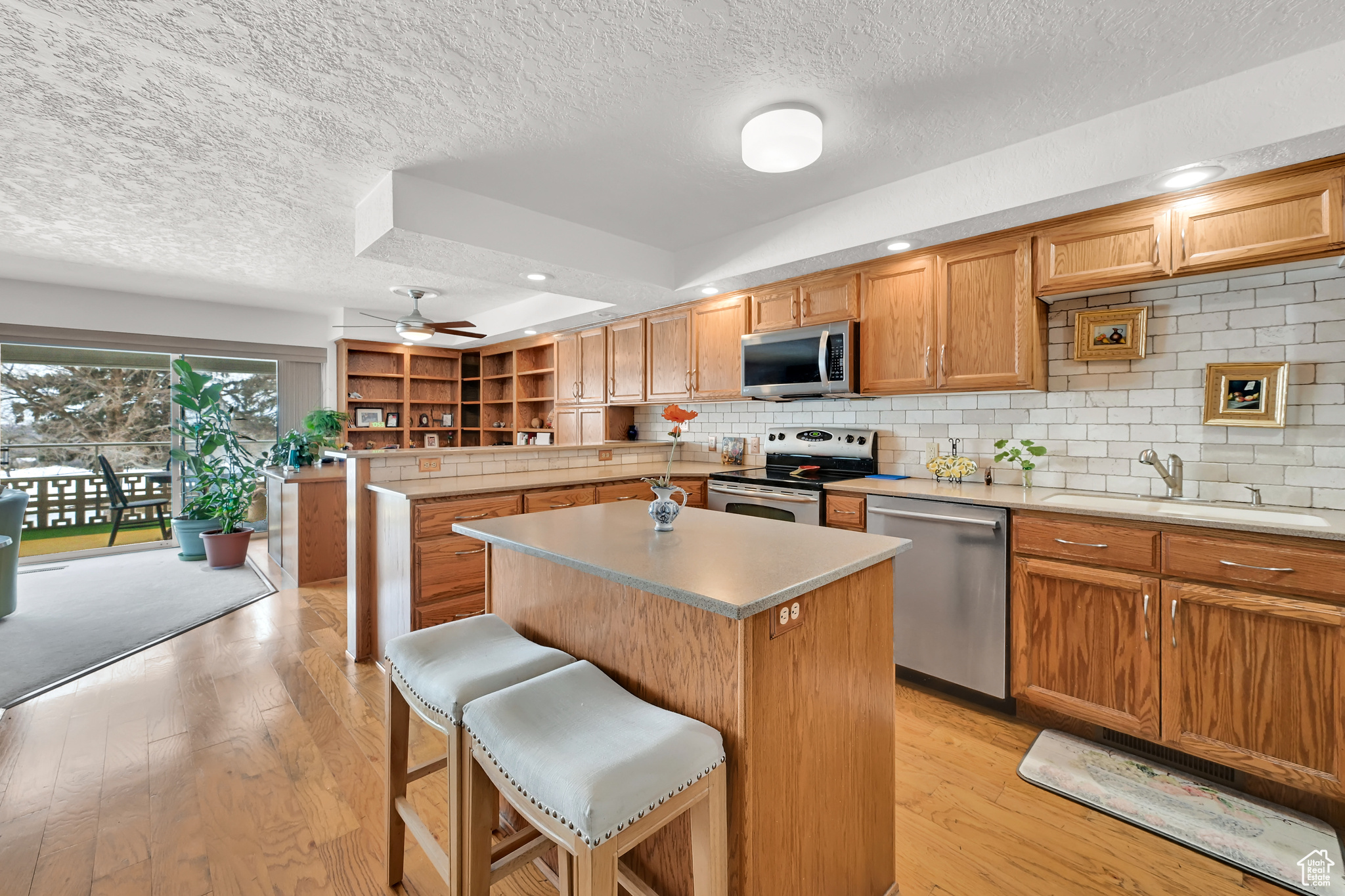 Kitchen with appliances with stainless steel finishes, a center island, light countertops, a kitchen bar, and a sink