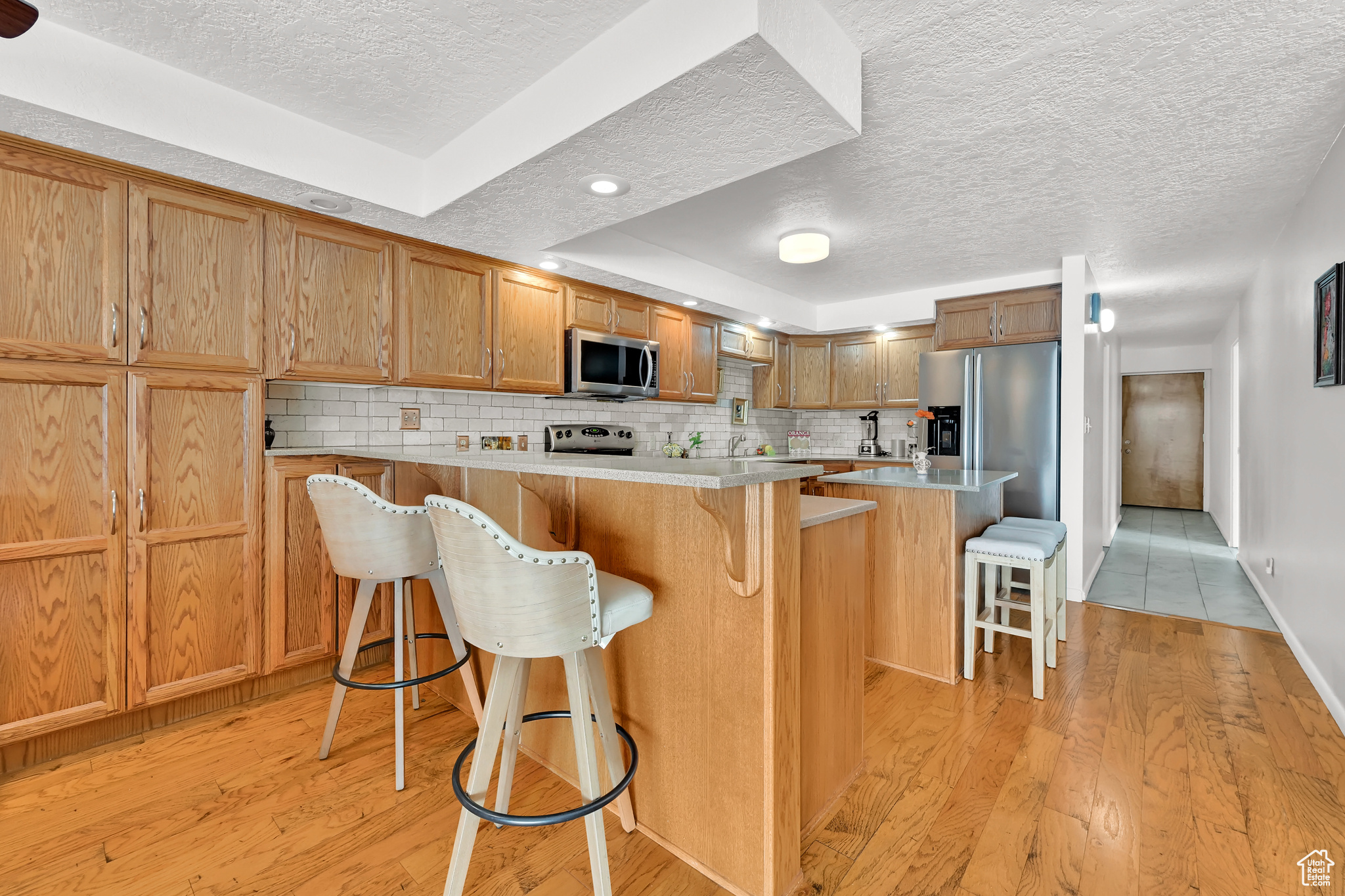 Kitchen featuring backsplash, a breakfast bar area, stainless steel appliances, and light countertops