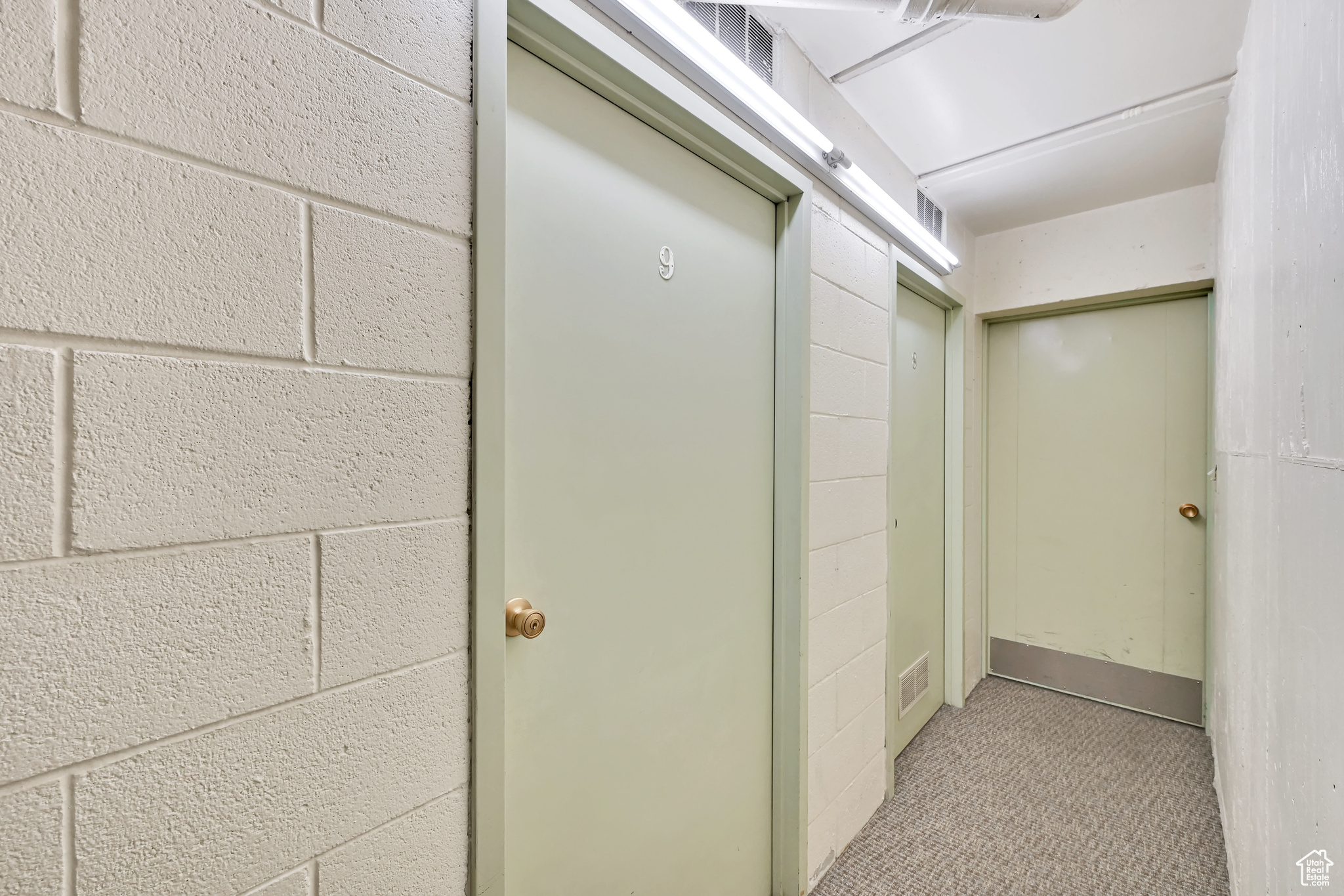 Room details with visible vents, carpet floors, and concrete block wall