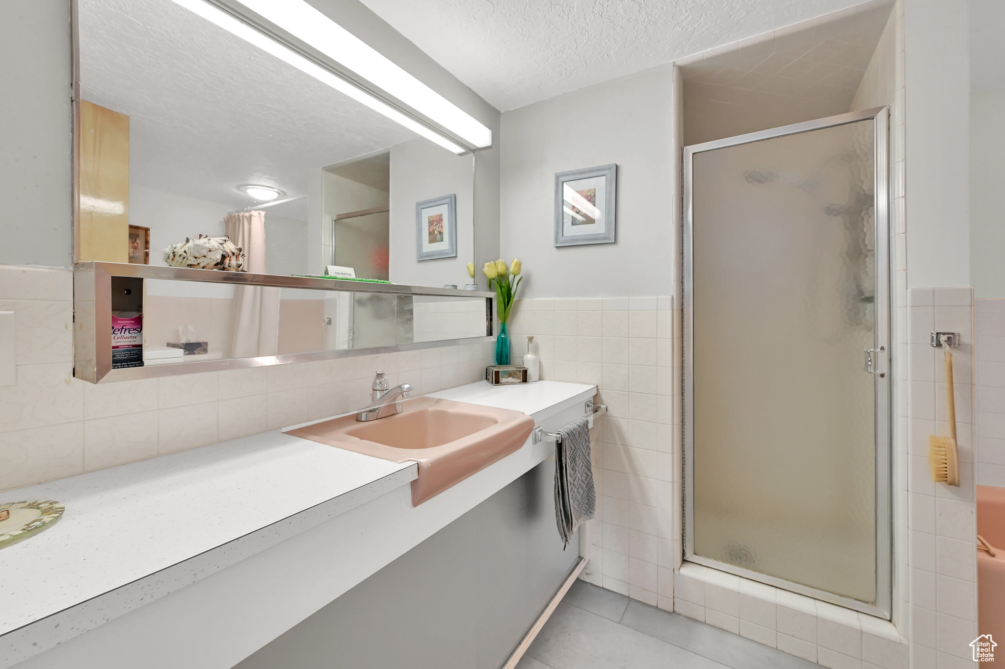 Bathroom featuring a textured ceiling, a stall shower, vanity, and tile walls