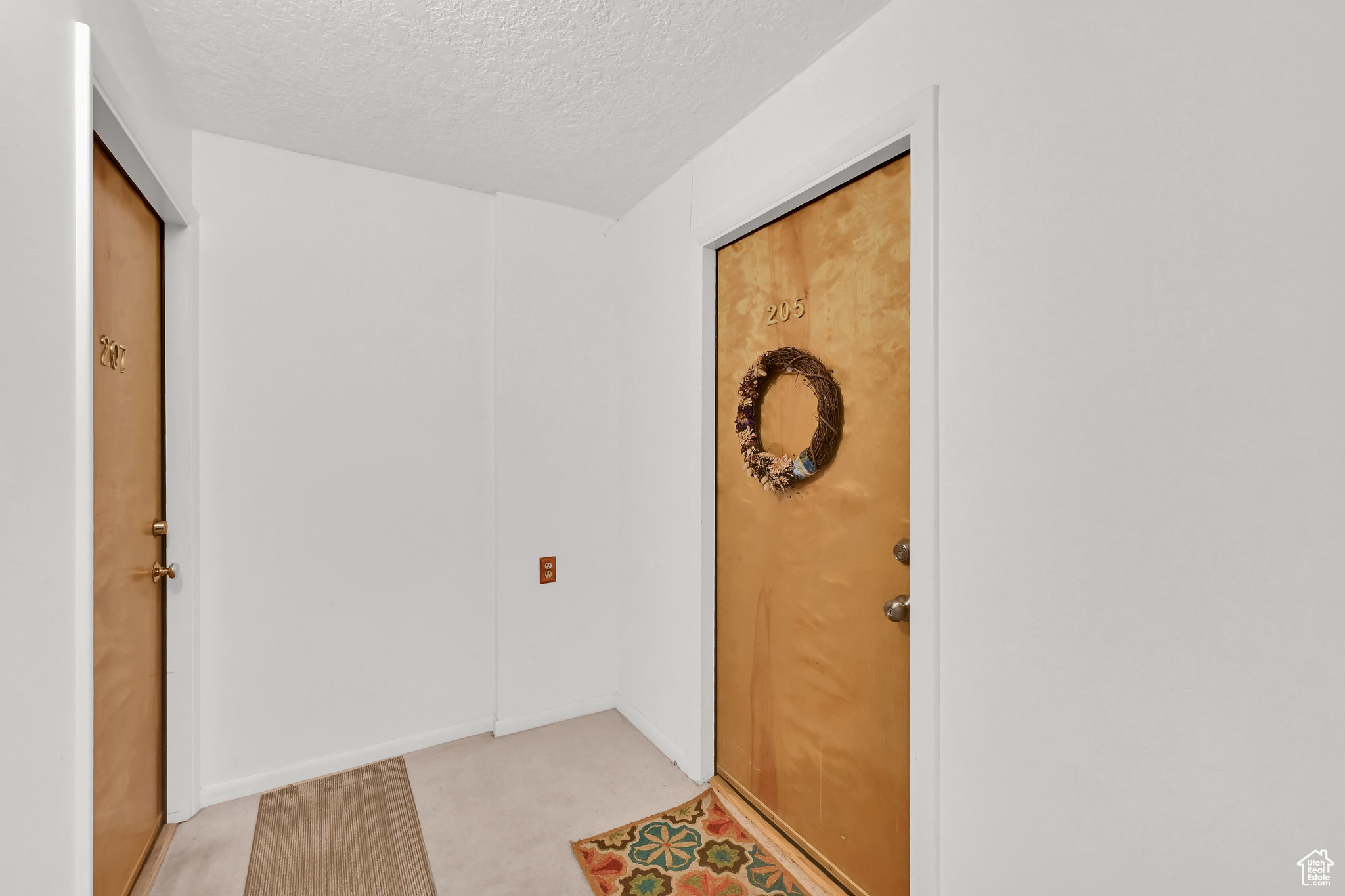 Interior space featuring light carpet, a textured ceiling, and baseboards