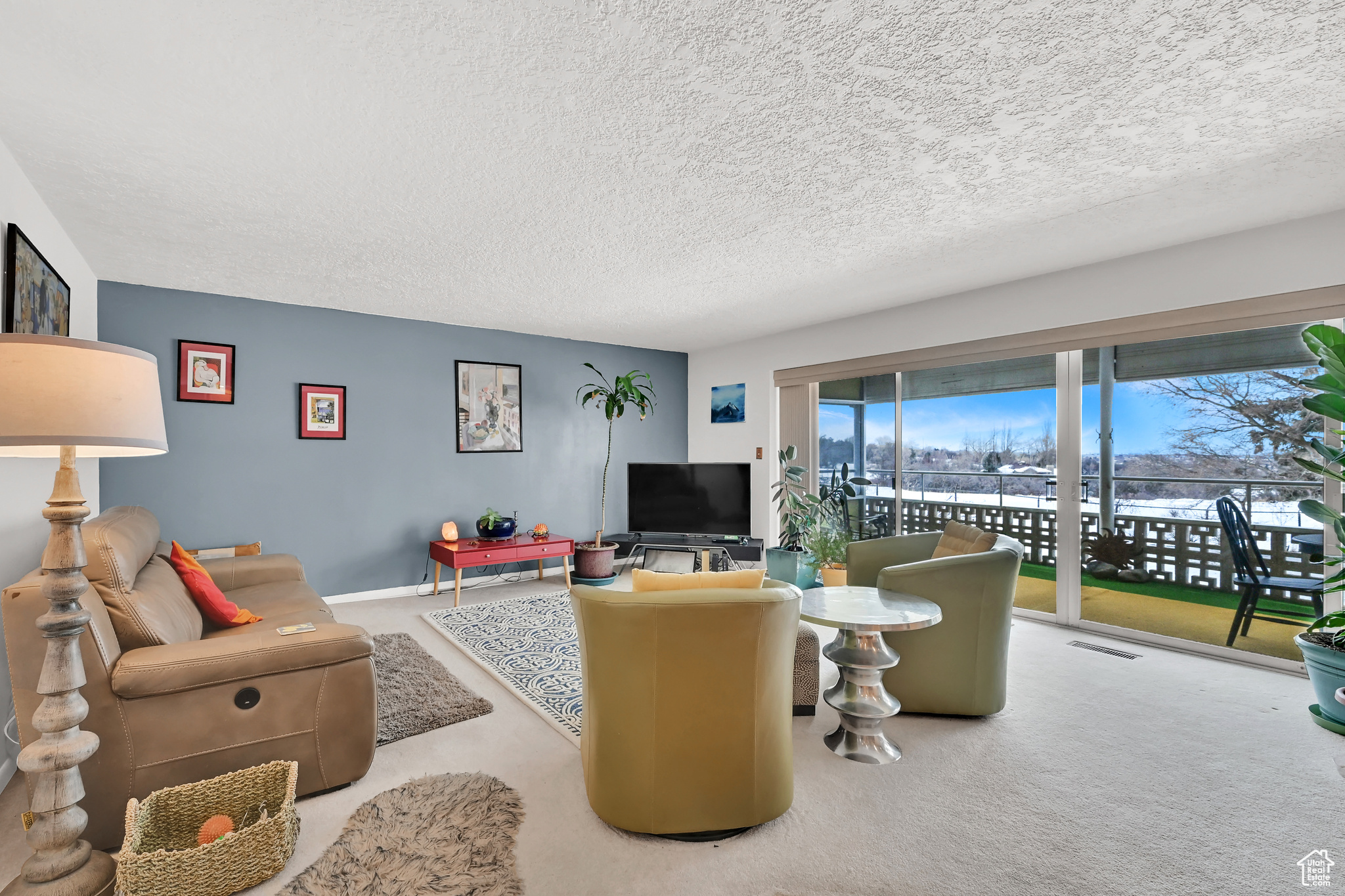 Living area featuring light carpet, a textured ceiling, and visible vents